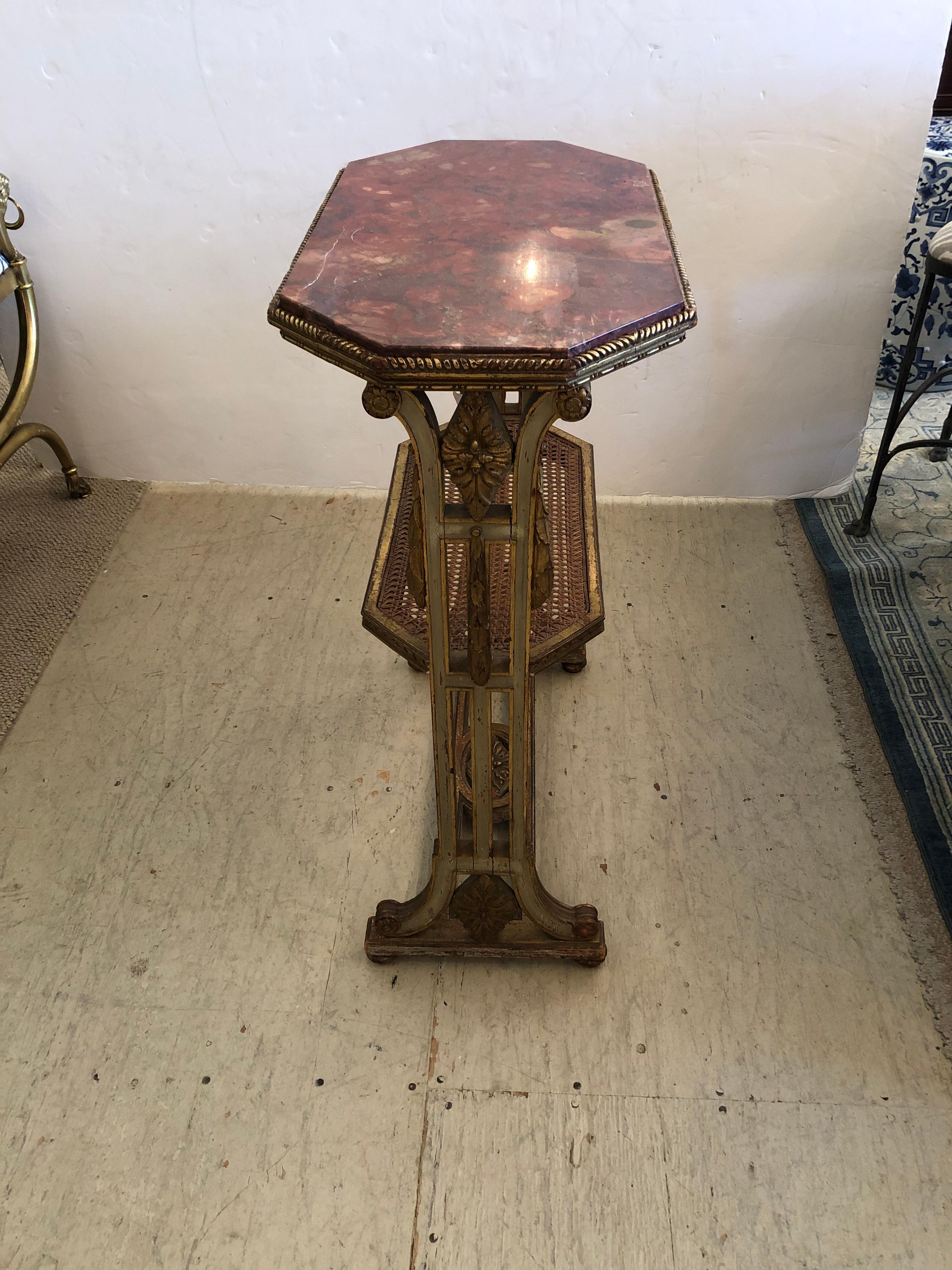 Unusually pretty rare shaped French Louis XVI style side table having octagonal marble top in a marvelous orangey rouge color palette on top of superb carved giltwood celadon/gray painted base with caned second lower tier.
Lower tier 17