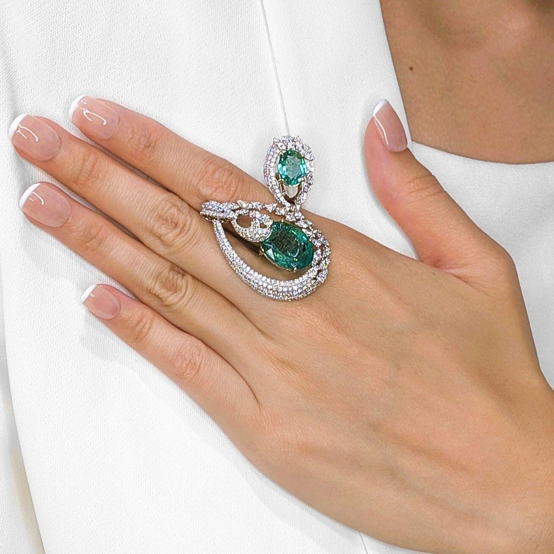 Make a statement of pure elegance with this breathtaking designer ring, crafted in 18K white gold. Featuring two radiant oval-cut emeralds totaling 10.26ct, their lush green hue is framed by 260 natural diamonds weighing 2.51ct for an irresistible