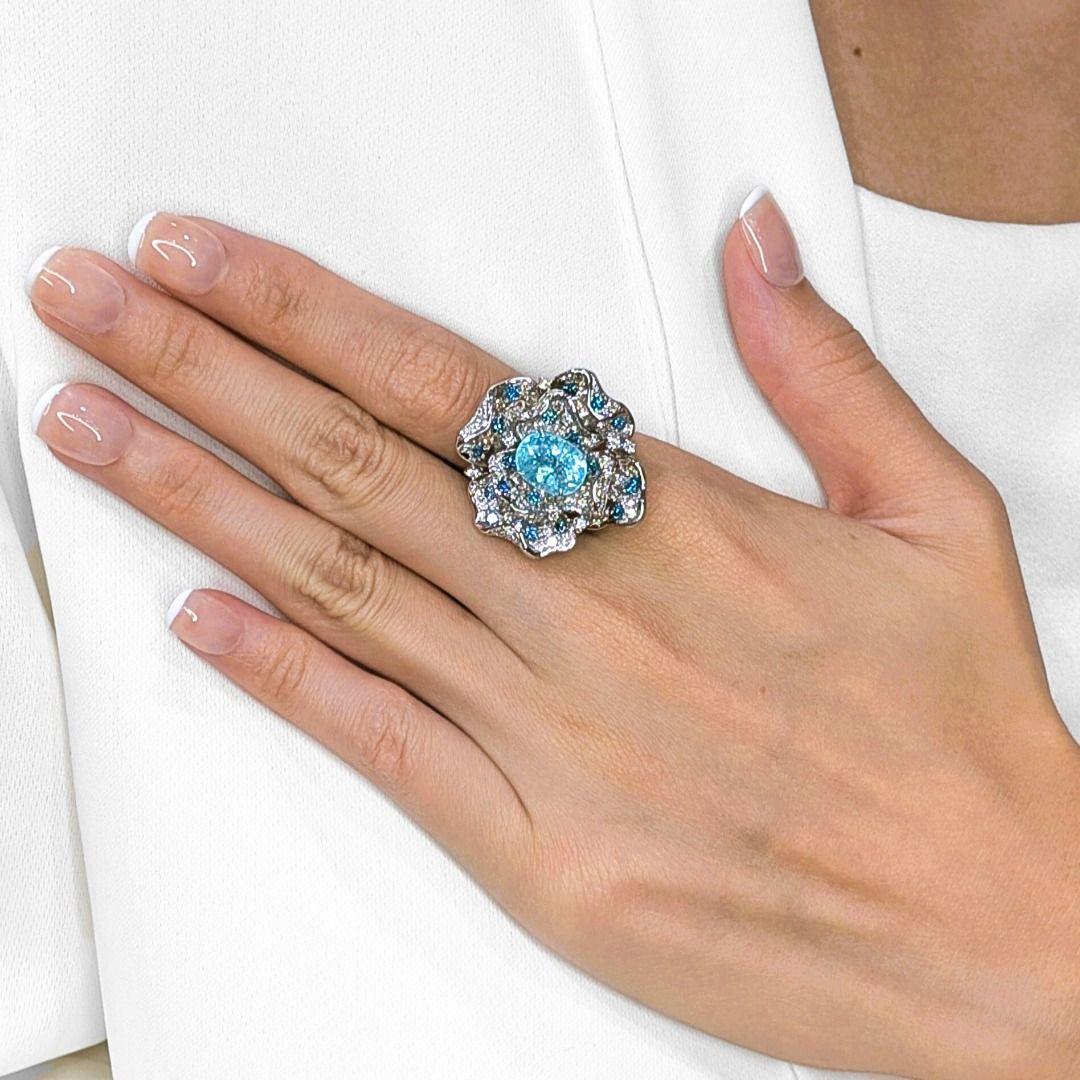 Una auténtica obra maestra del arte y la rareza, este anillo se centra en una fascinante turmalina Paraiba oval de 4,11 ct, que brilla con su característico tono azul intenso. Alrededor de la pieza central hay un deslumbrante diseño de inspiración