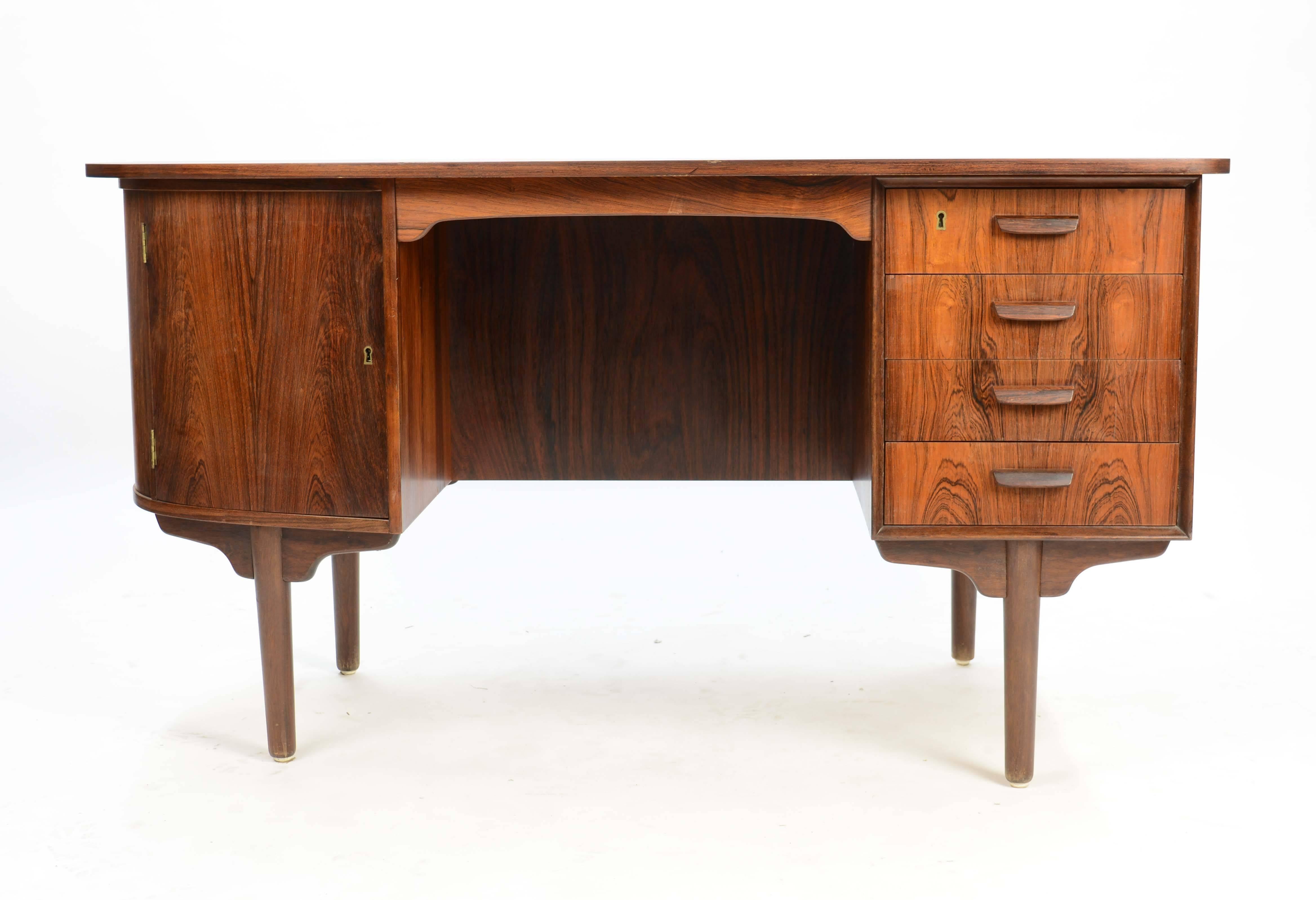 This stunning desk in covered in rosewood veneers that make it command attention for it's elegant and sophistication of Danish design and craftmanship. The desk featured built in bookcase and cabinets. It has two locking bookcase and four drawers.