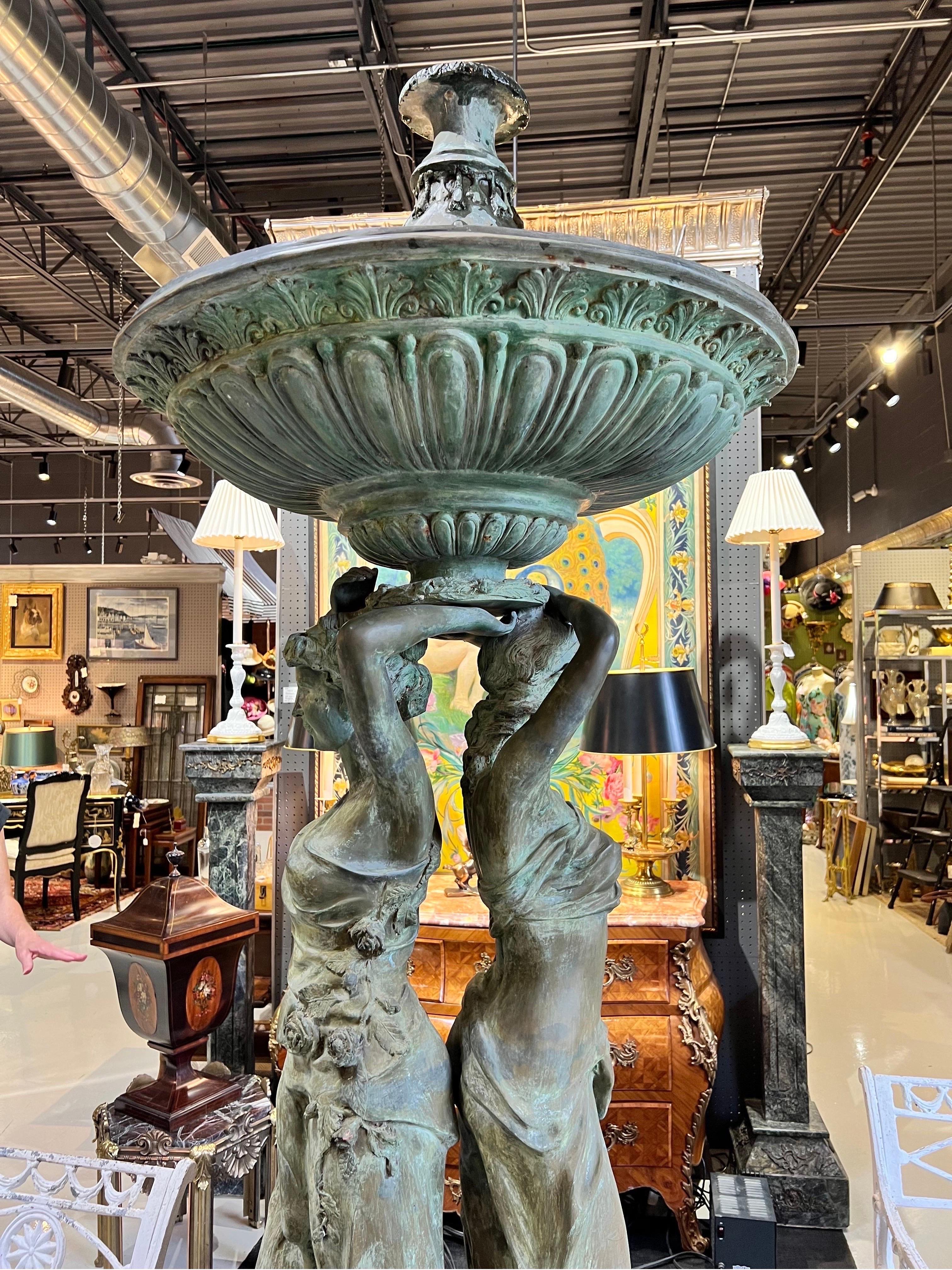 Towering antique bronze fountain with two beautiful goddesses holding up the large water bowl. This stately and beautifully made fountain will give your garden all the elegance of early 20th century Italy - from whence it hails. This immediate