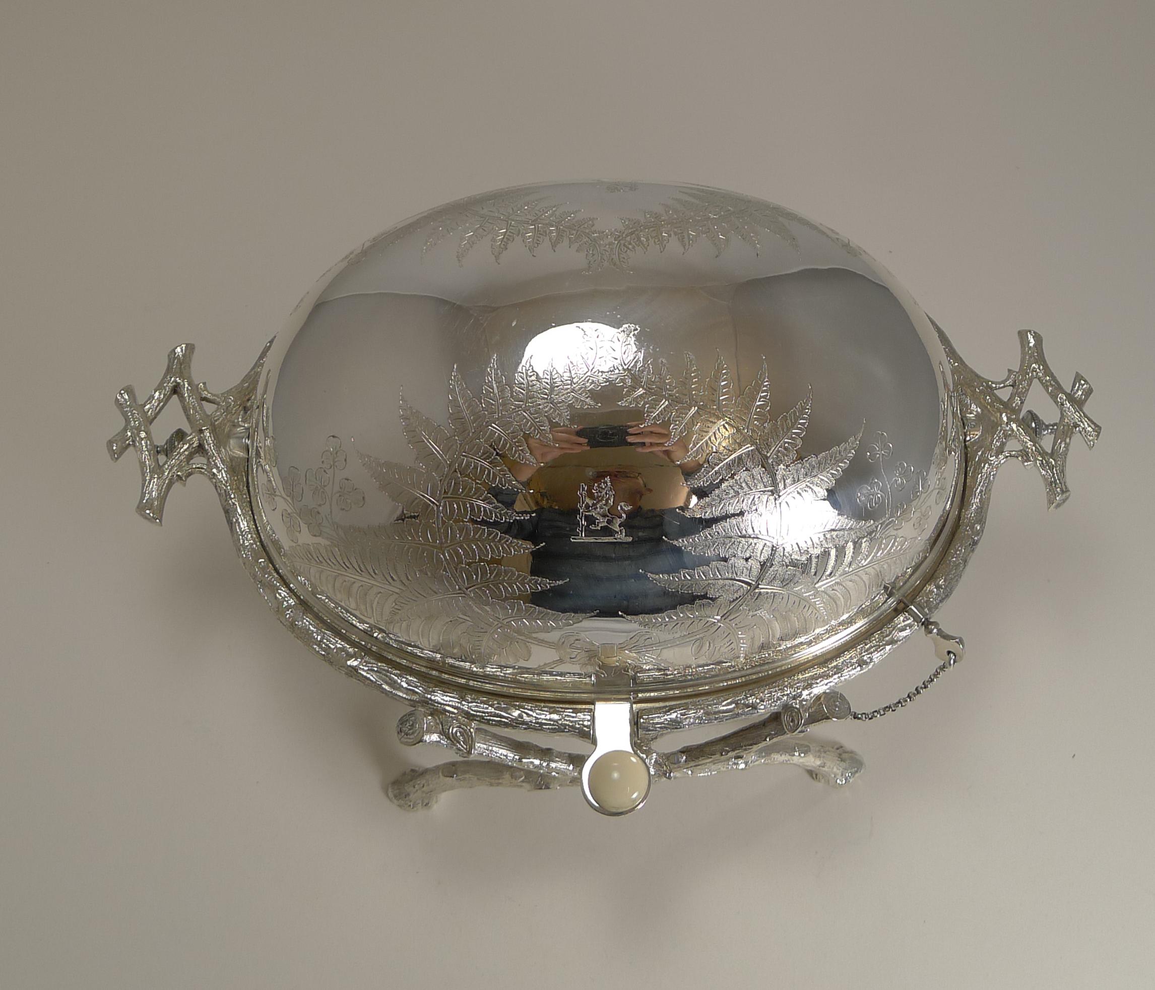 A magnificent Victorian revolving breakfast dish by Furber and Son of Cheltenham.

The frame is beautifully decorated in the form of wooden logs and the domed top lavishly engraved with Ferns tied each side with a ribbon and bow, very Victorian