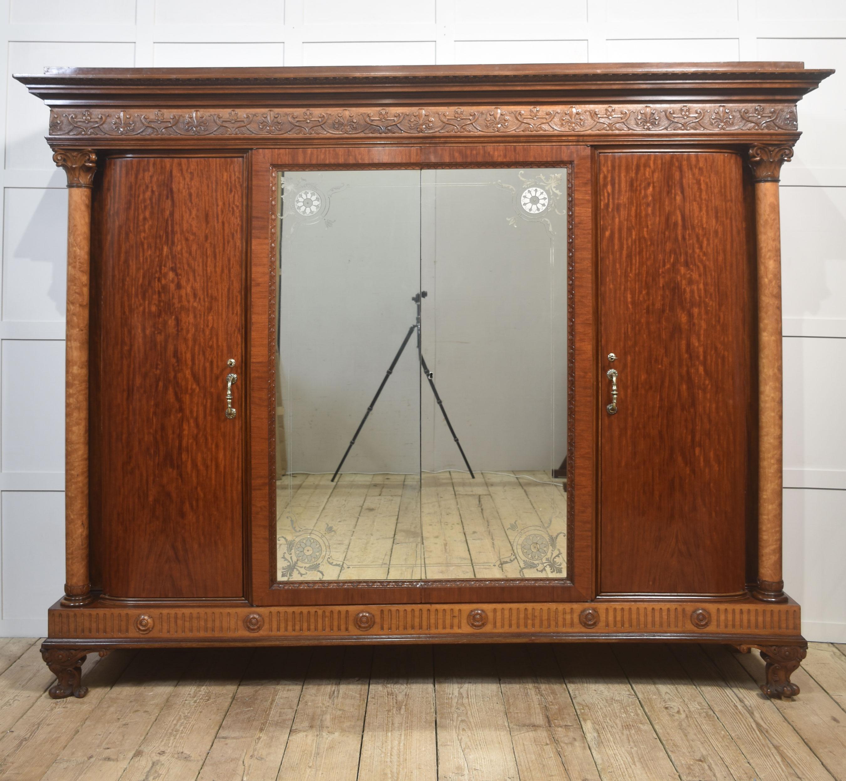 Questo eccezionale armadio a quattro ante della fine del XIX o dell'inizio del XX secolo mostra una superba maestria, materiali ricchi e una grande presenza architettonica. Costruito in mogano splendidamente scolpito, presenta suggestive colonne
