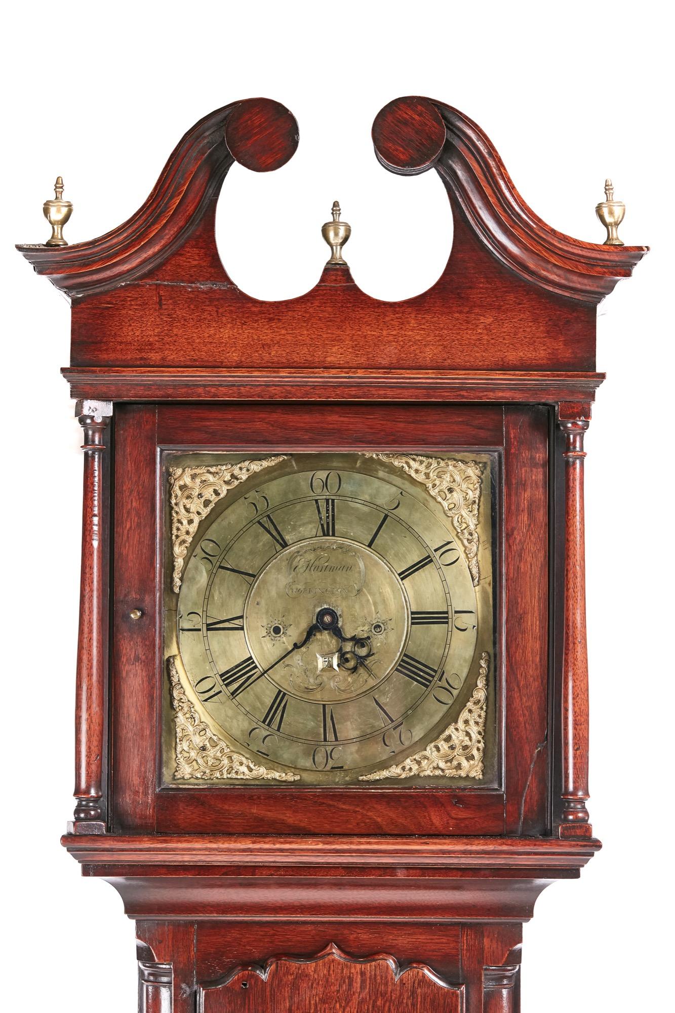 This is a magnificent example of a George II brass face red walnut longcase clock. The hood having and elegant broken swan-neck pediment and brass finials, a fine long door with a shaped top, quarter rounded columns to the case, standing on shaped