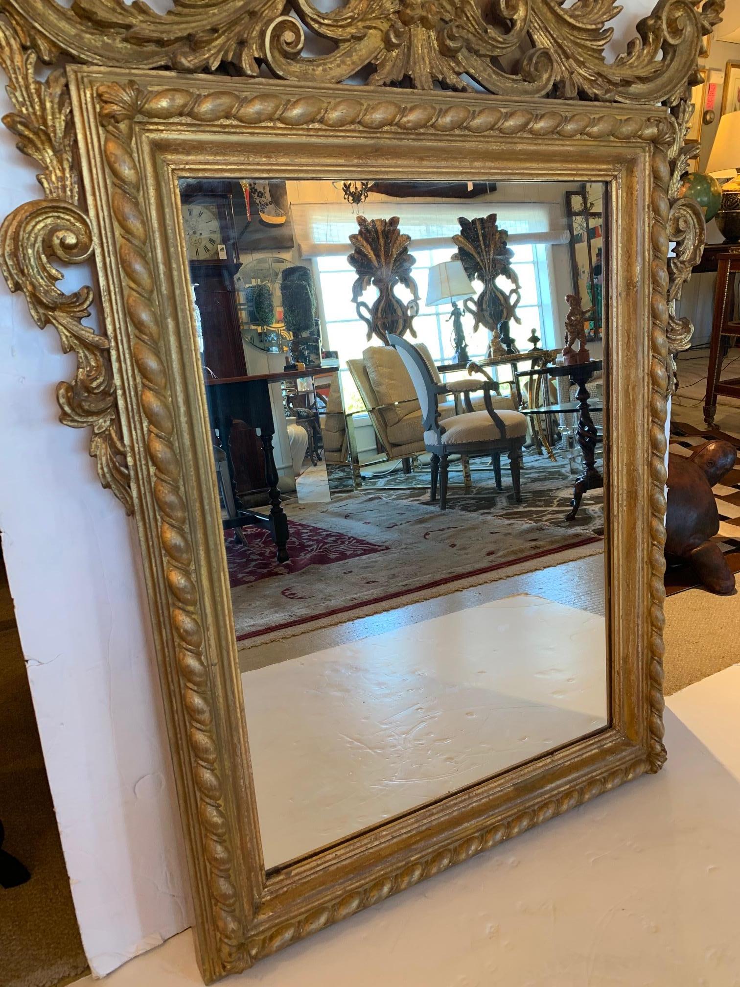 Ornately carved giltwood wall mirror from Italy having particularly lovely curlicues and flourishes around the top.