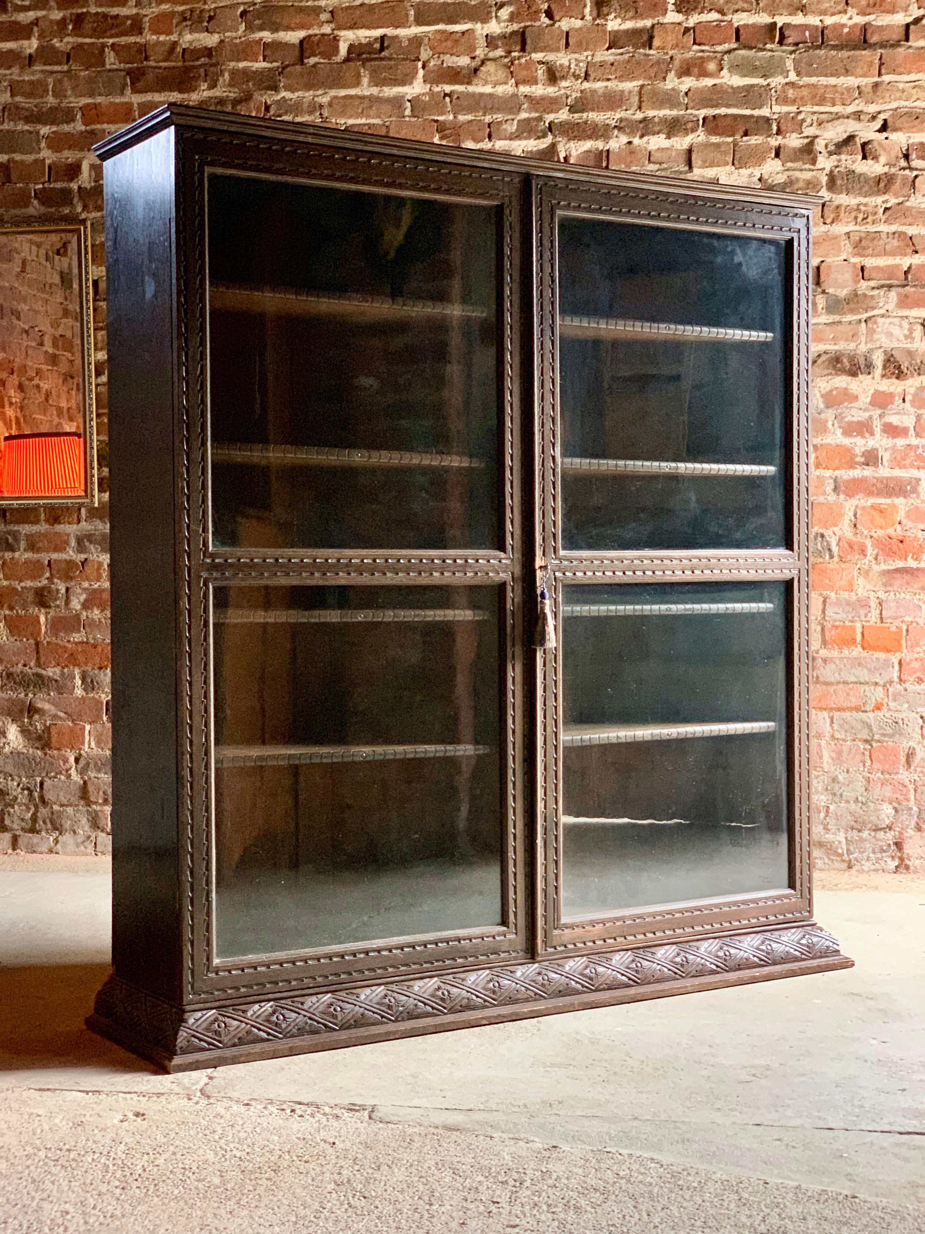 Magnificent Antique oak two-door glazed bookcase early twentieth century circa 1900, the corniced top over two glazed doors, with carved decoration and eight adjustable shelves, raised on a carved plinth base

Antique

Adjustable