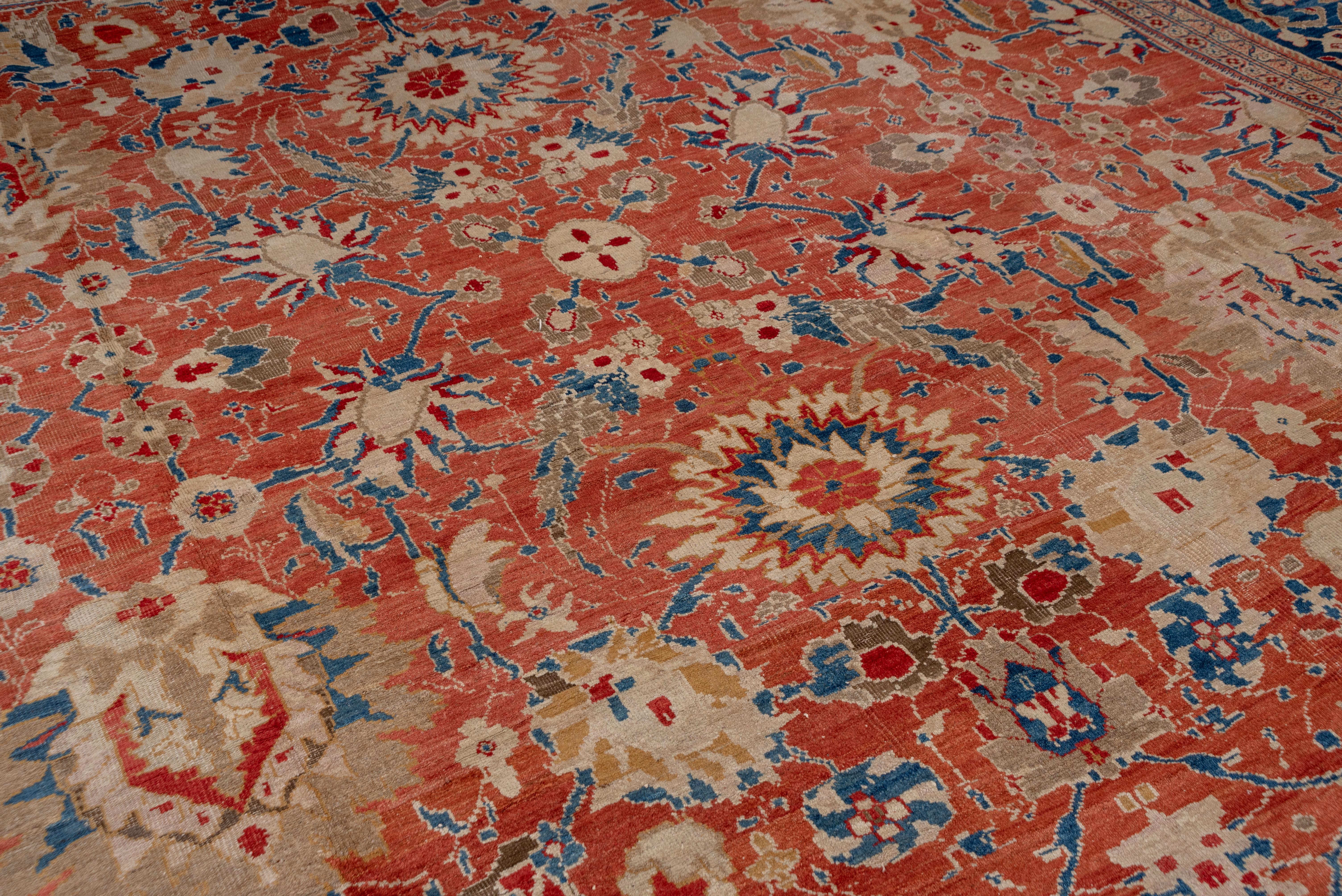 This magnificent west Persian village carpet shows a rust-red field overall-patterned with giant palmettes, nested sharp petal rosettes and an artistic variety of layered lancet leaves, smaller bi tonal profile palmettes and small flowers. Luminous