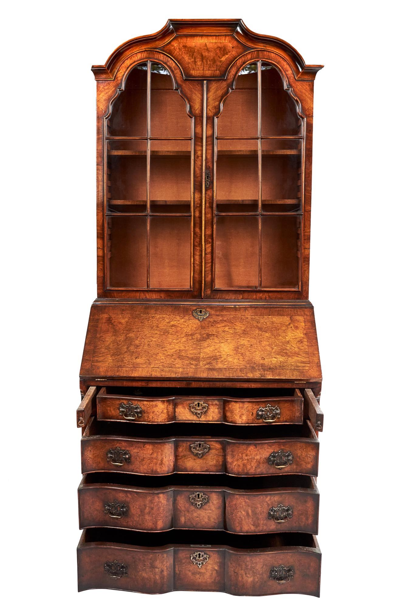 This is an outstanding Queen Anne revival walnut bureau bookcase having an attractive shaped moulded top with a pair of dome topped doors. The pretty cross banded bureau fall opens to reveal a leather inset and a lovely shaped interior with a centre