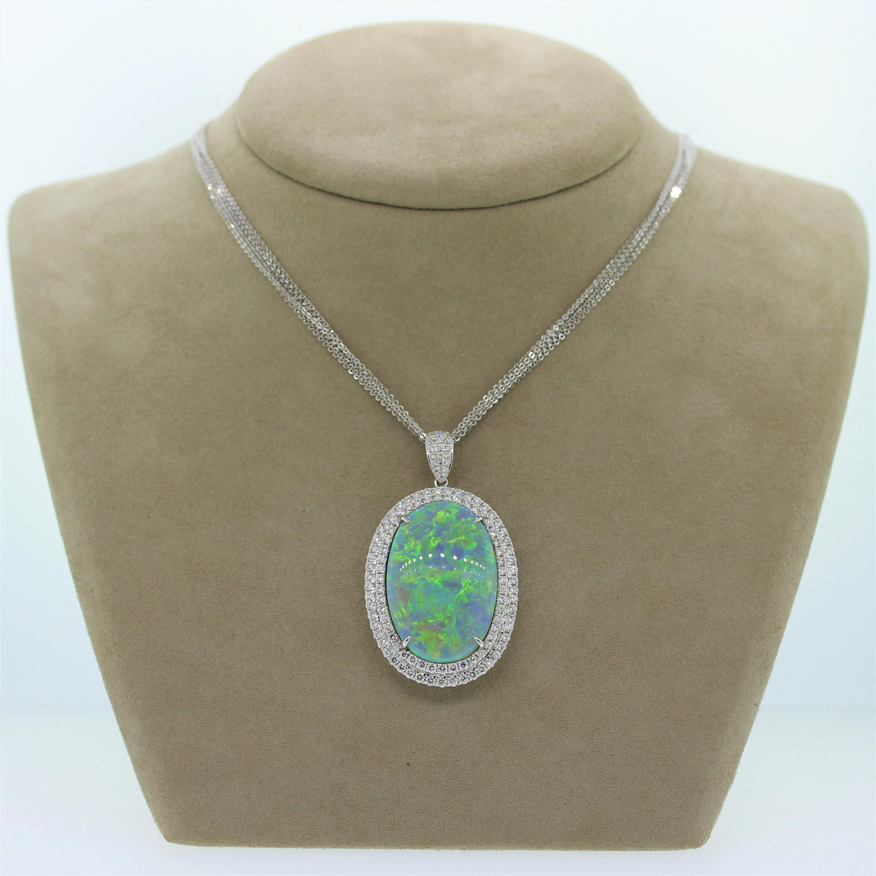 A contemporary pendant featuring a large and impressive 39.76 carat Australian opal in a 18K white gold setting. The oval shaped gem shows strong play of color with bright flashes of blue, green, and orange. It is encased in a double halo of 3.28