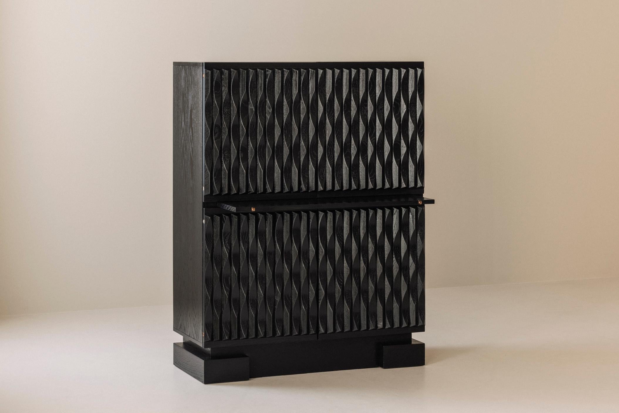 Magnifica credenza brutalista di Maison Aurora, Belgio, anni '70. Costruito interamente in rovere tinto scuro, il pezzo presenta ante profondamente scolpite che creano un'audace presenza architettonica. La sezione superiore si apre per rivelare un