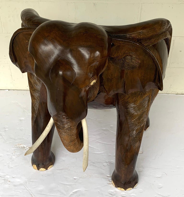 Magnificent carved hardwood elephant chair
A comfortable, substantial realistically carved, chair, modelled as a standing elephant. The raised back and sides carved as the head and ears, with carved painted eyes and tusks with carved trunk pointed