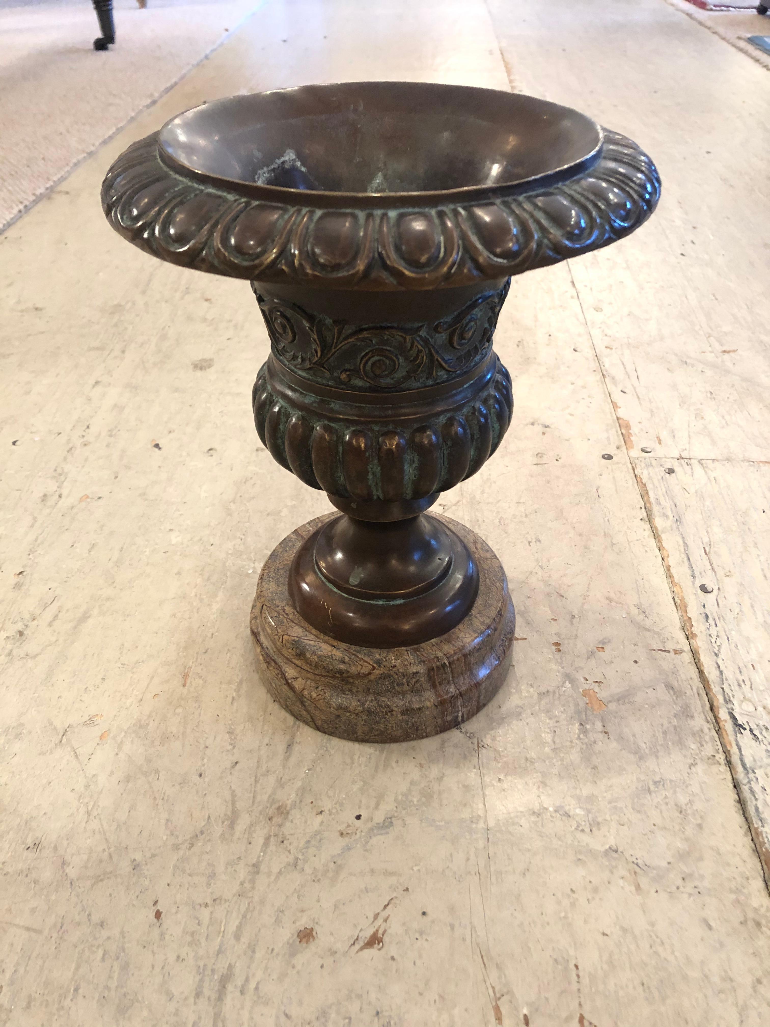 Luscious bronze urn on marble base having classical decoration and warm patina.