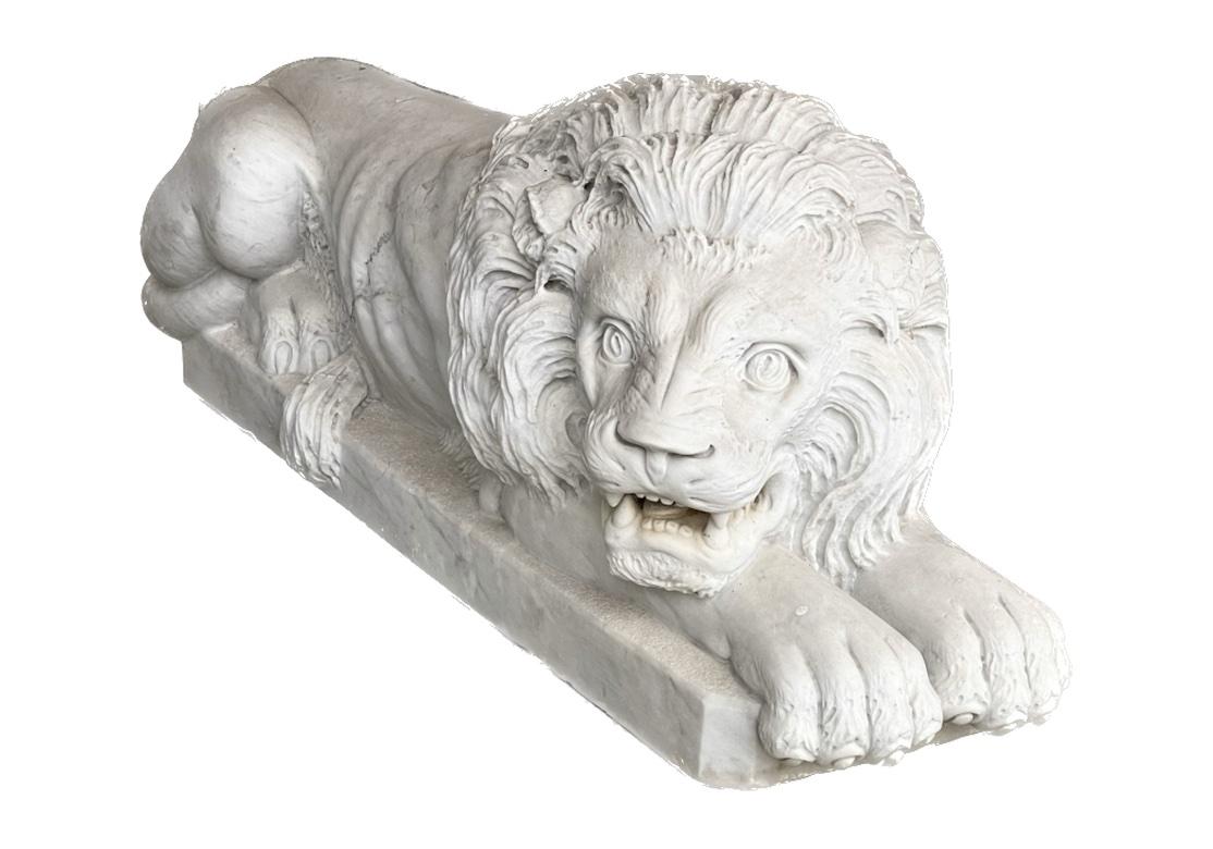 A Pair of Male Lions in carved marble resting on octagonal attached slab bases. Originally purchased in London and having incredible classic form. One of the Lions rests with his head resting on crossed paws with eyes closed, his companion alert and