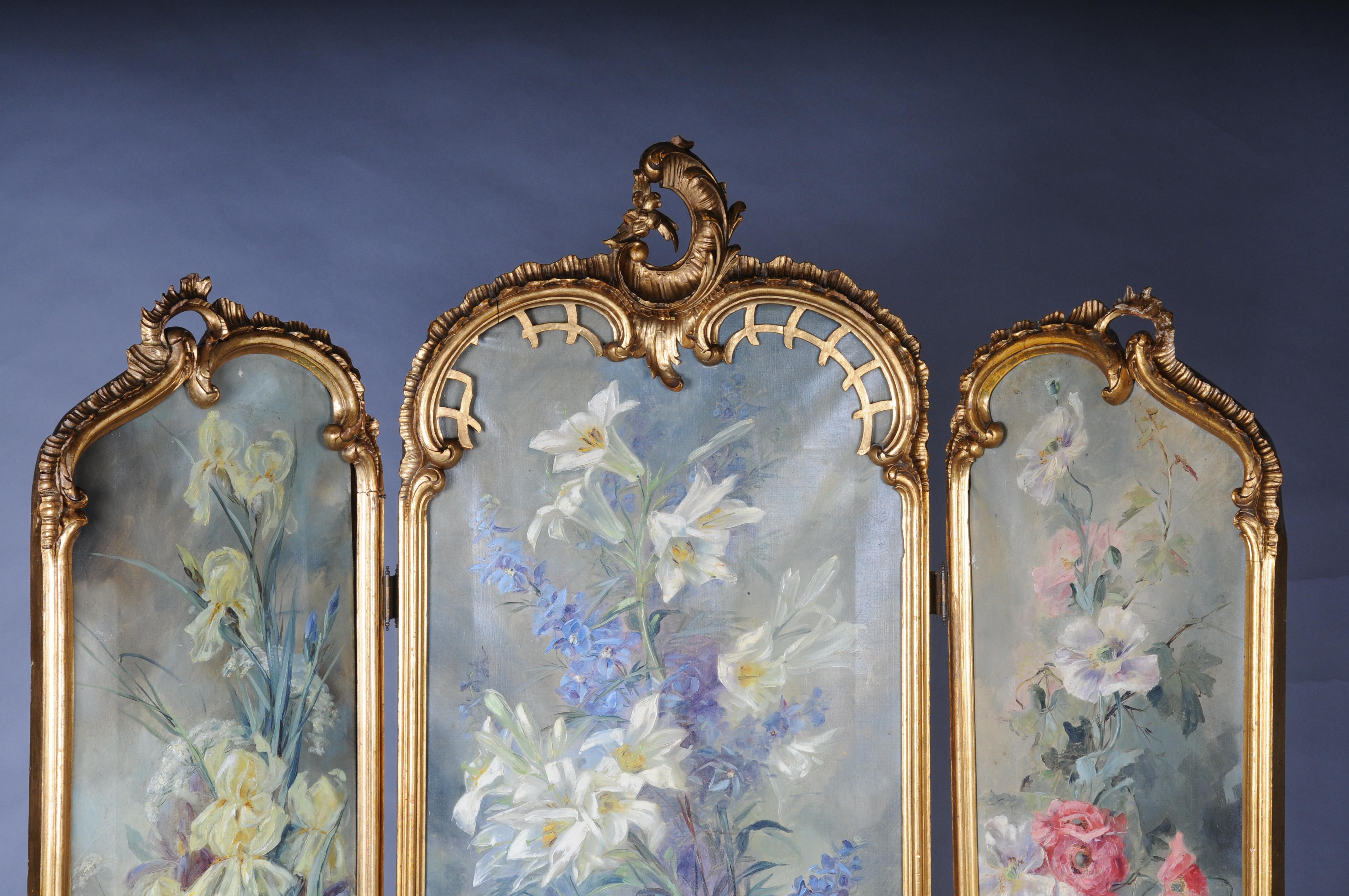 Magnificent decorative Rococo folding screen from the Belle Époque.

Paravent/Room divider from consisting of three panels (triptych). Finely carved and gilded wooden frame. Canvas panels painted with lush, blooming floral bouquets, signed M.