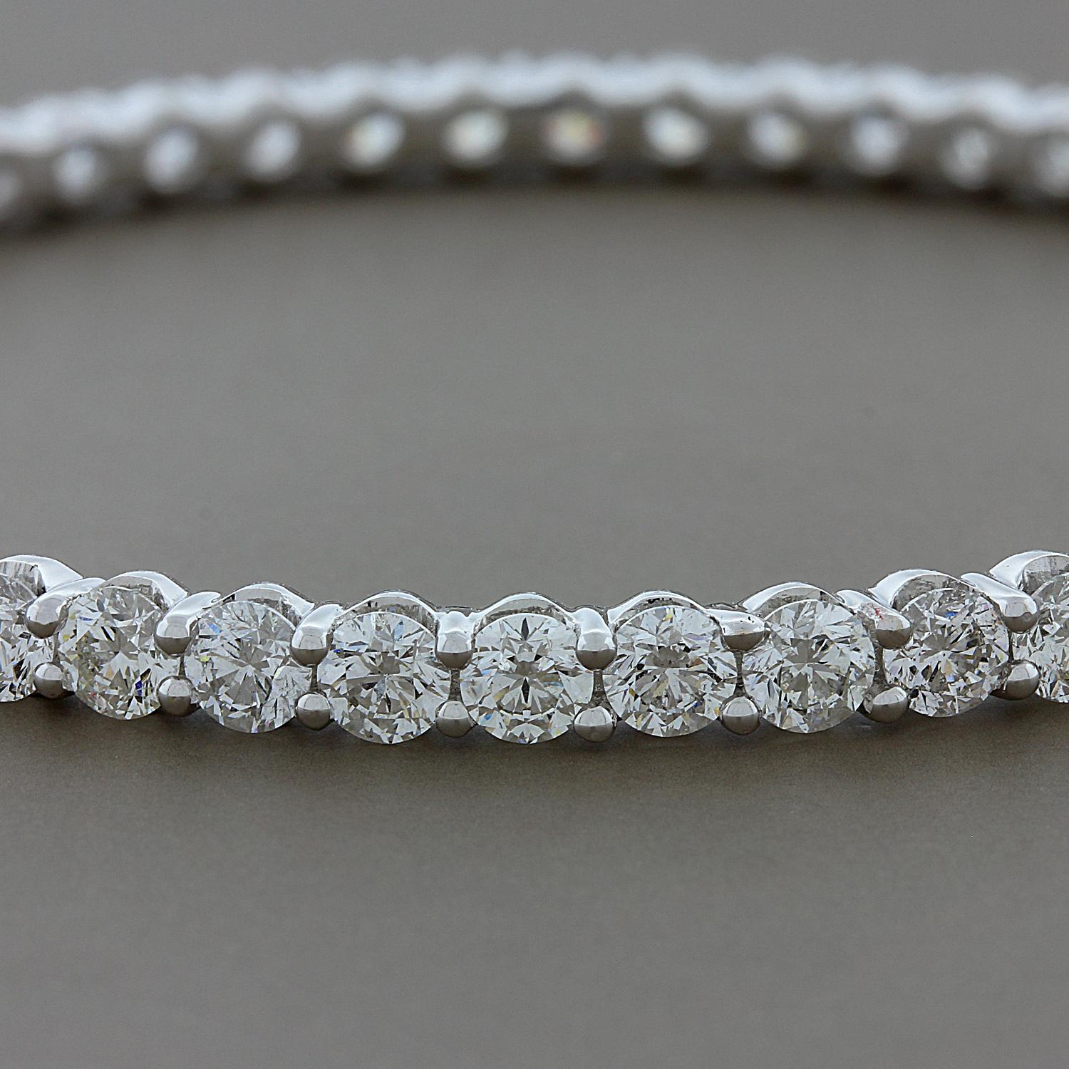 A luxurious eternity bangle showcasing 52 round cut VS quality diamonds weighing 12.98 carats.  The colorless diamonds are set in a classic four prong setting in 18K white gold.  A magnificent bracelet to have sparkling on its own or to stack with