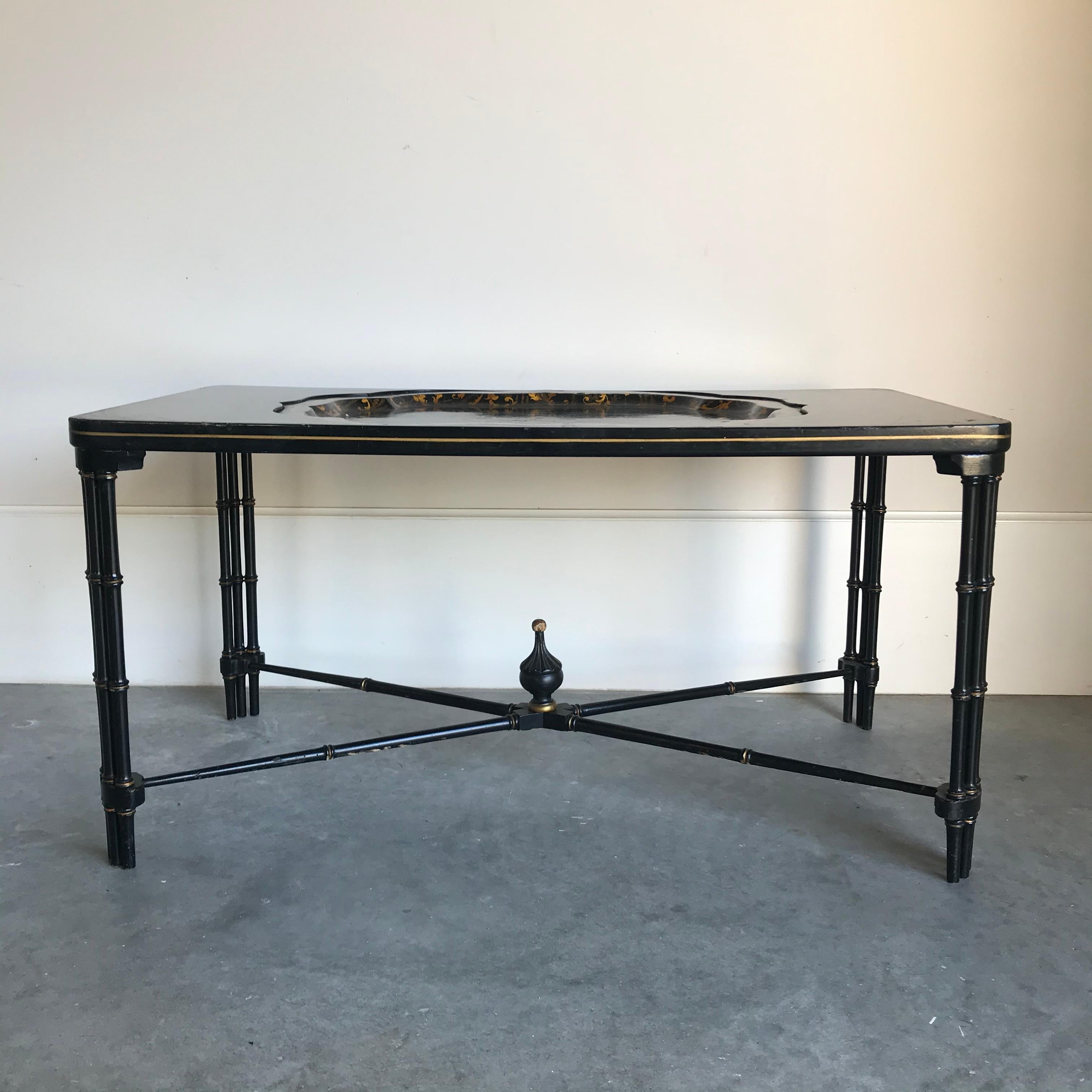 English Regency style black lacquered tray top coffee table with decorative floral design in gold inset in a black lacquered and gilt double faux bamboo leg base. Lovely stretcher underneath with central decorative finial.

#4268.

  