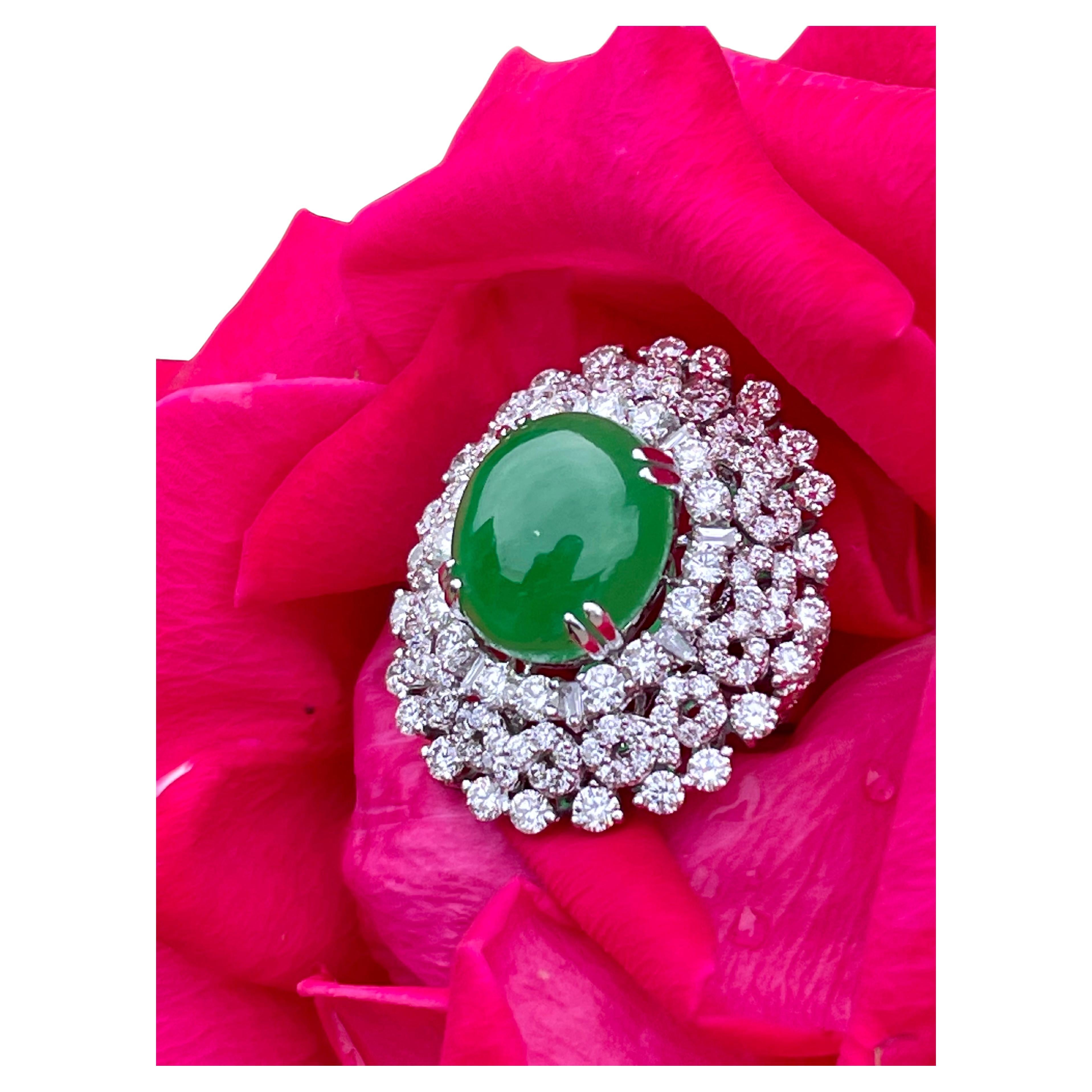 Magnificent and totally dazzling, 18 karat white gold large estate jade and diamond cocktail ring features a beautiful 12.30 carat green jade cabochon stone in the center, surrounded by a sparkling triple halo of round and circular pattern prong set
