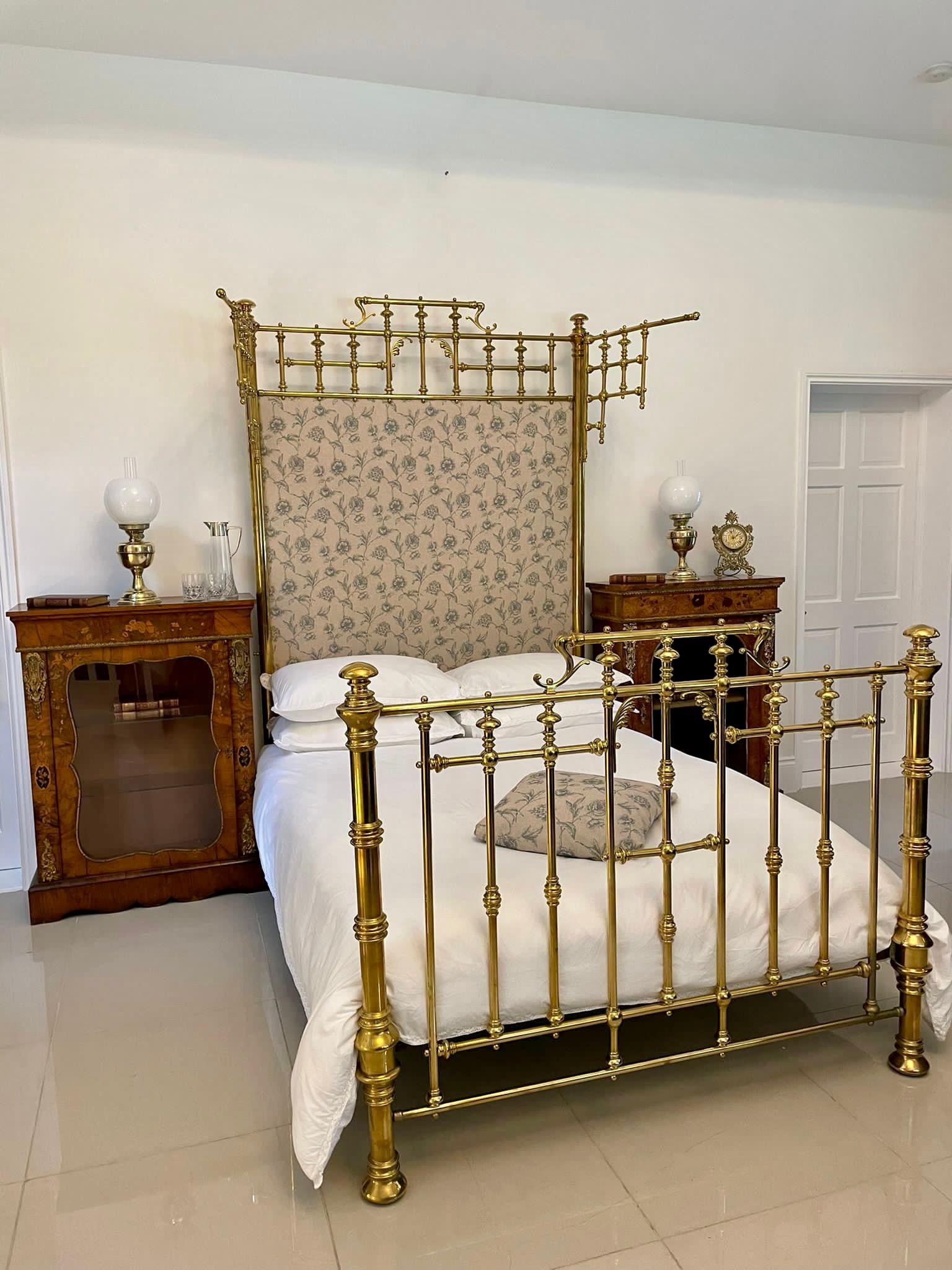 Magnificent exhibition quality antique Victorian gilded solid brass half tester double bed having a newly reupholstered back in a quality fabric flanked by two circular brass column posts with ornate swing out wings which can be used to hang fabric