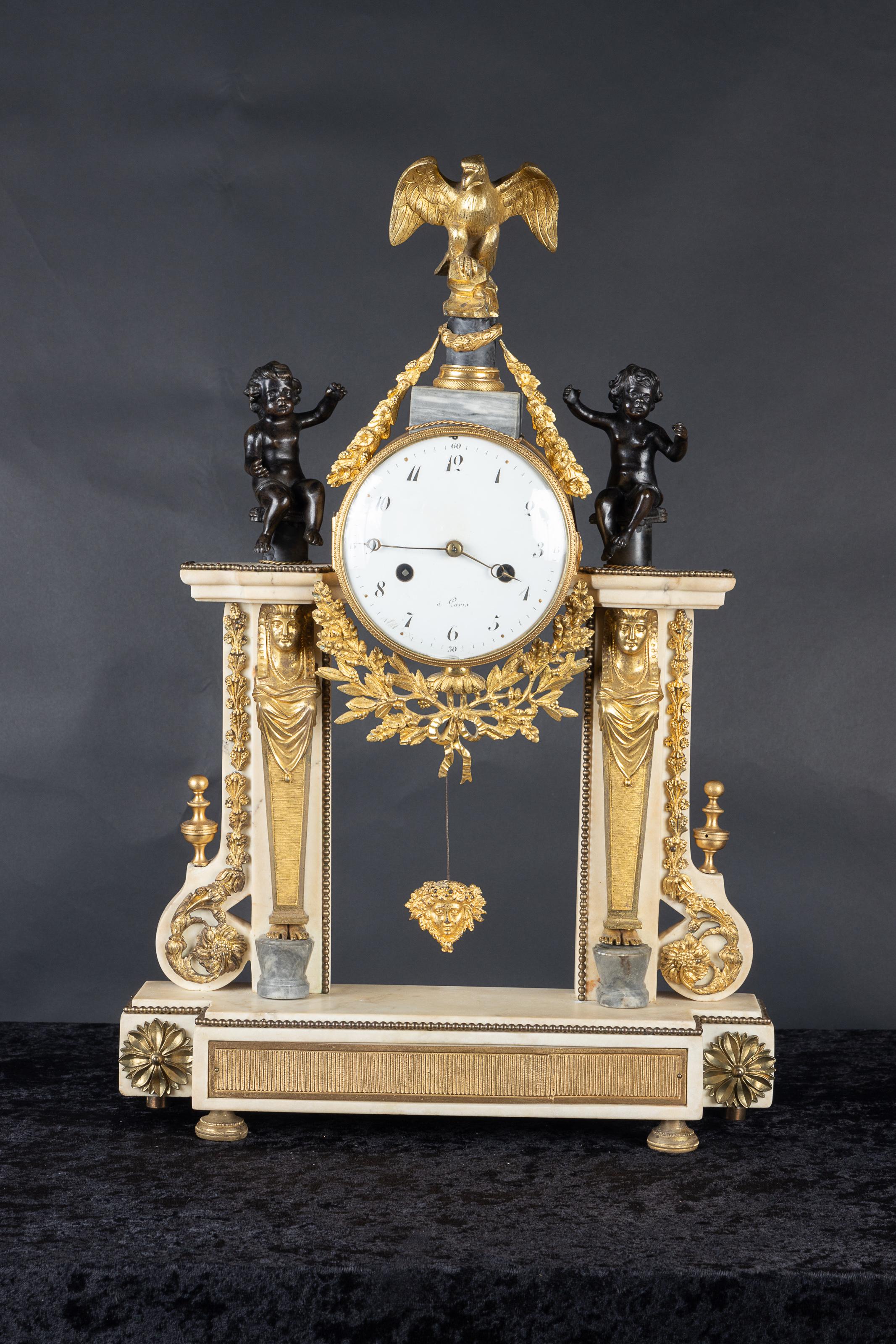 Magnificent French 19th century Empire white marble mantel clock adorned with bronze d’ore mounts in a floriate design. The piece features a female figure on either side wearing an Egyptian headdress, classic to the Empire style.   Round white