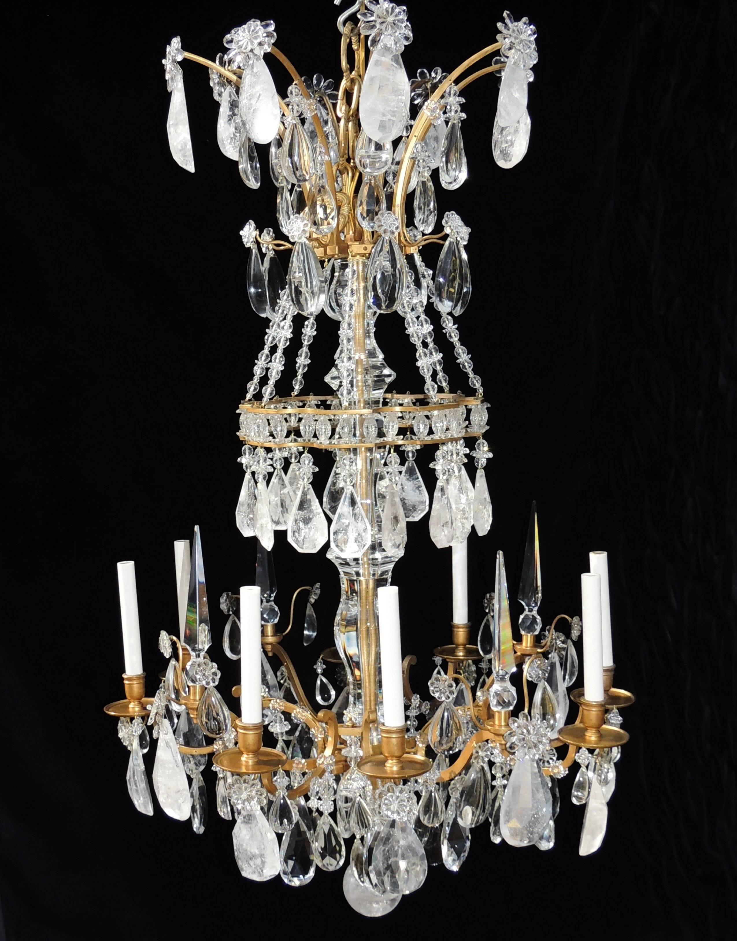 Dieser majestätische achtflammige Kronleuchter aus Doré-Bronze hat mehrere Schichten aus klarem und Bergkristall, die jedes Teil umschließen. In der Mitte befindet sich ein großer Kristallschaft und wunderschöne Spitzen, die die Kerzenlichter