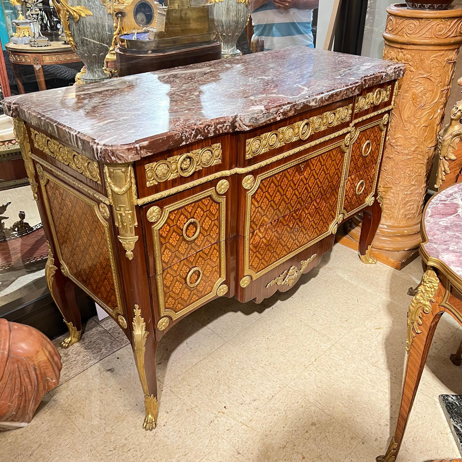 Antique (19th century) commode in the Louis XVI style exhibiting the finest craftsmanship, after the original model by Jean Henri Riesener,  including parquetry inlaid fruitwood veneer and ormolu bronze mounts of exceptional quality.  Made in Paris