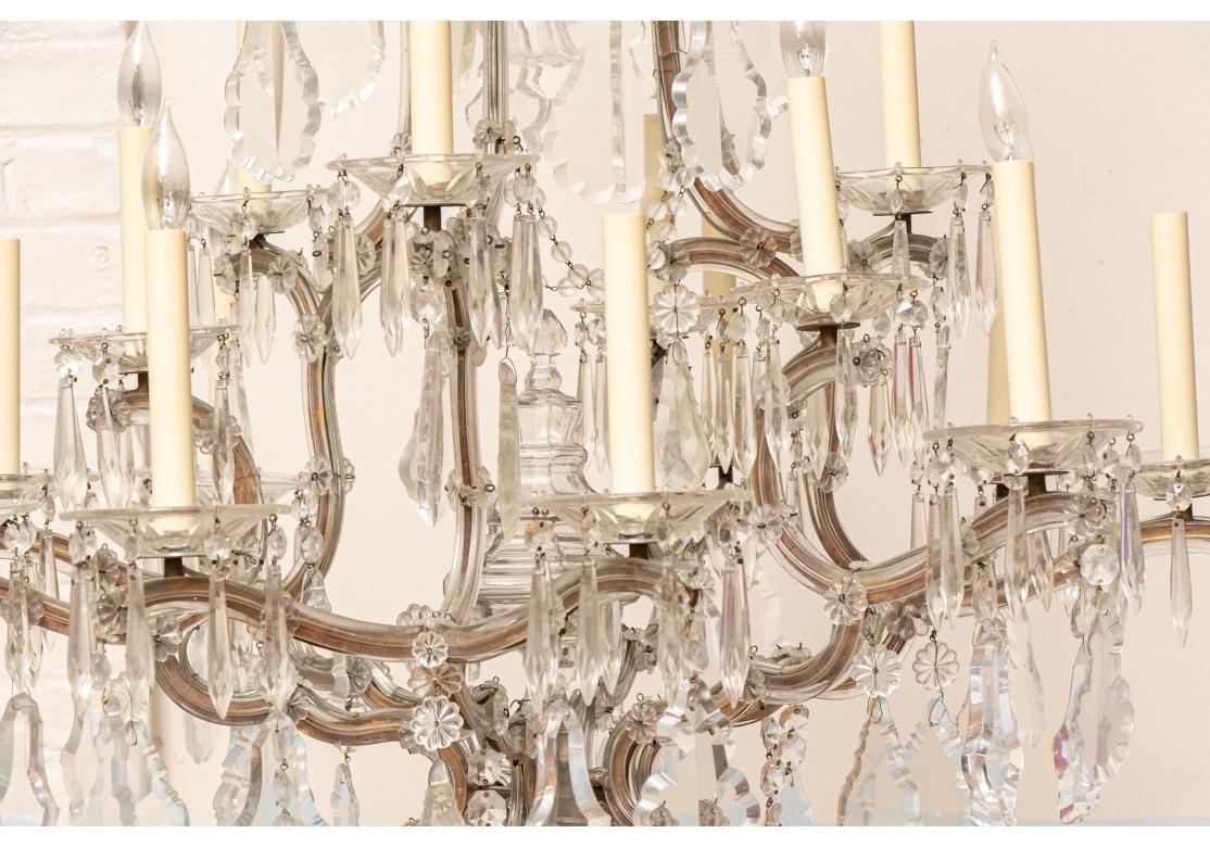 Un raffinato lampadario di cristallo in stile francese con 6 C.I.C. a scorrimento  rami di cristallo con rosette e ciascuna emissione di due o tre candele accese con cristalli prismatici sfaccettati intorno alle coppe. Il lampadario ha una cuspide