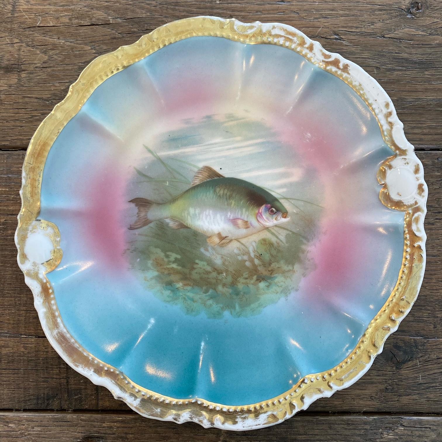 A vibrant set of 12 hand painted gold gilt fish plates with matching large platter and gravy or sauce boat. Each plate is beautifully shaped and accented with 24 karat gold, hand painted with a variety of fish and fauna. Marvelous color palette of