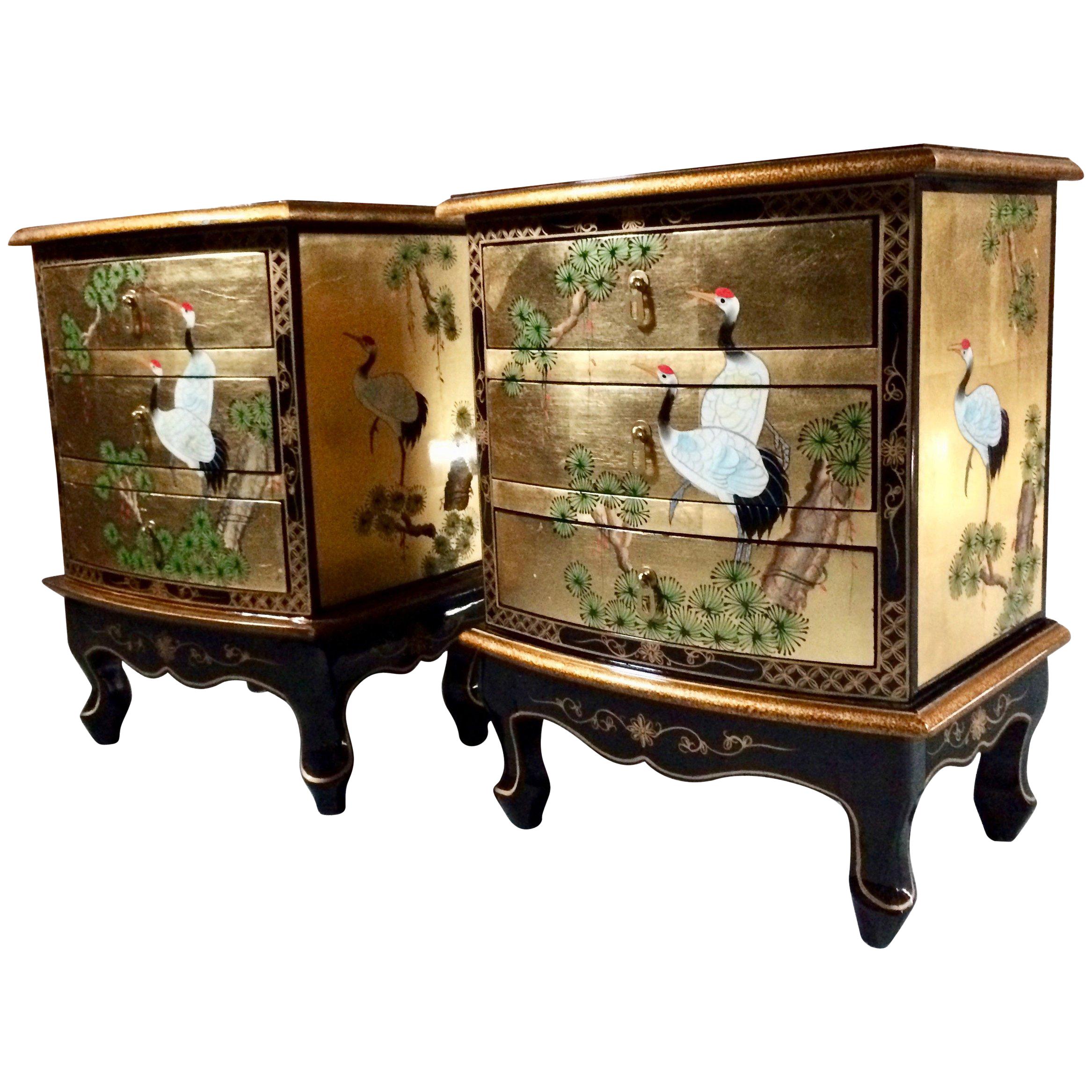 A stunning pair of late 20th century Japanese nightstands bedside tables and matching trunk, the lacquered finish with images of exotic cranes and lotus trees, finished in golds and reds, the overhanging rectangular top over three green felt lined