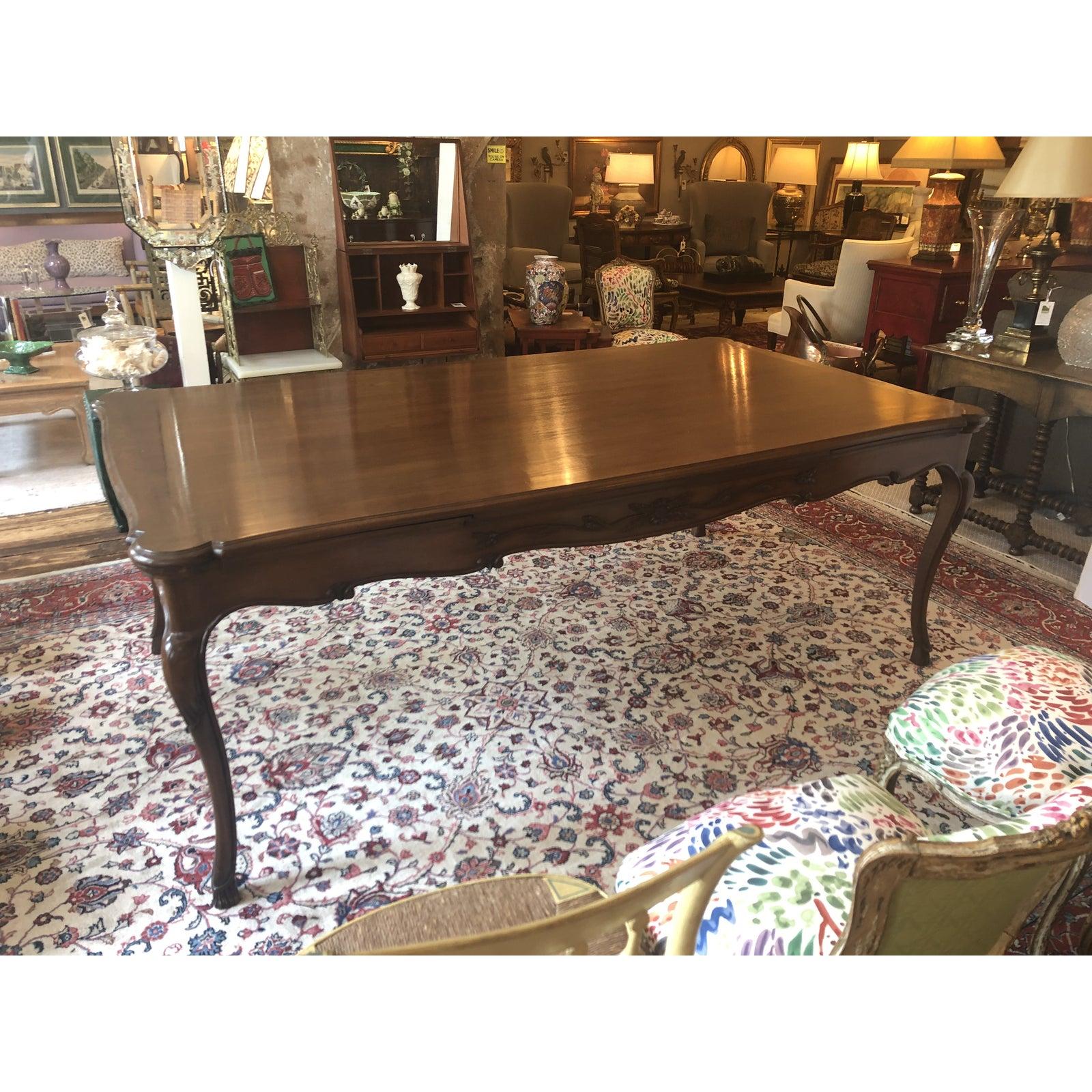 A magnificent carved walnut 7 foot French Provincial style dining table having hidden leaves at each end that pull out to create a grand almost 11 foot table. The apron has beautiful carvings with flowers and foliage and w the lovely legs are