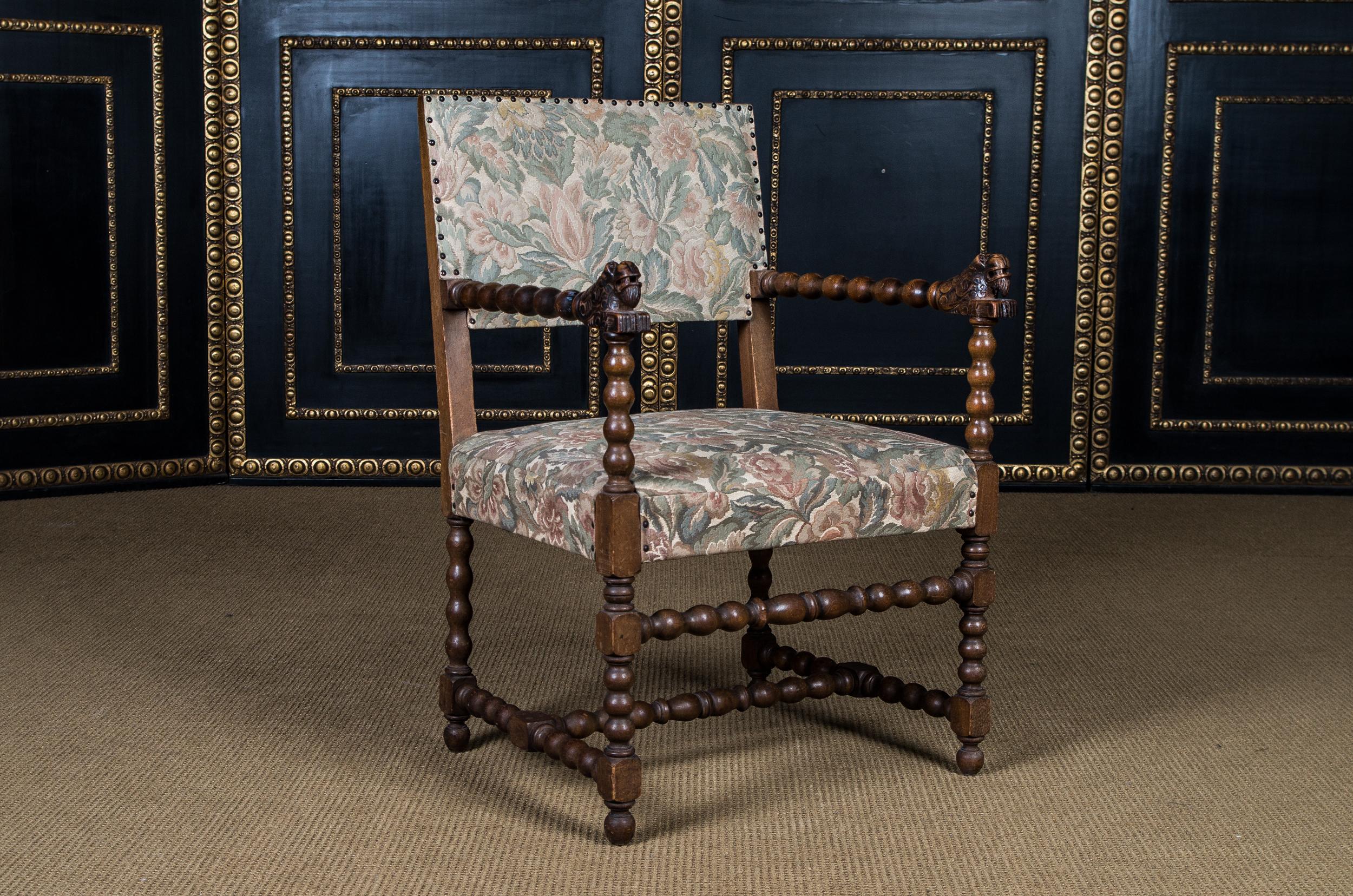 Massive oak. On four turned legs. Wide seat flanked by two turned armrests. High backrest. Seat and back covered with tapestry in Classic design.