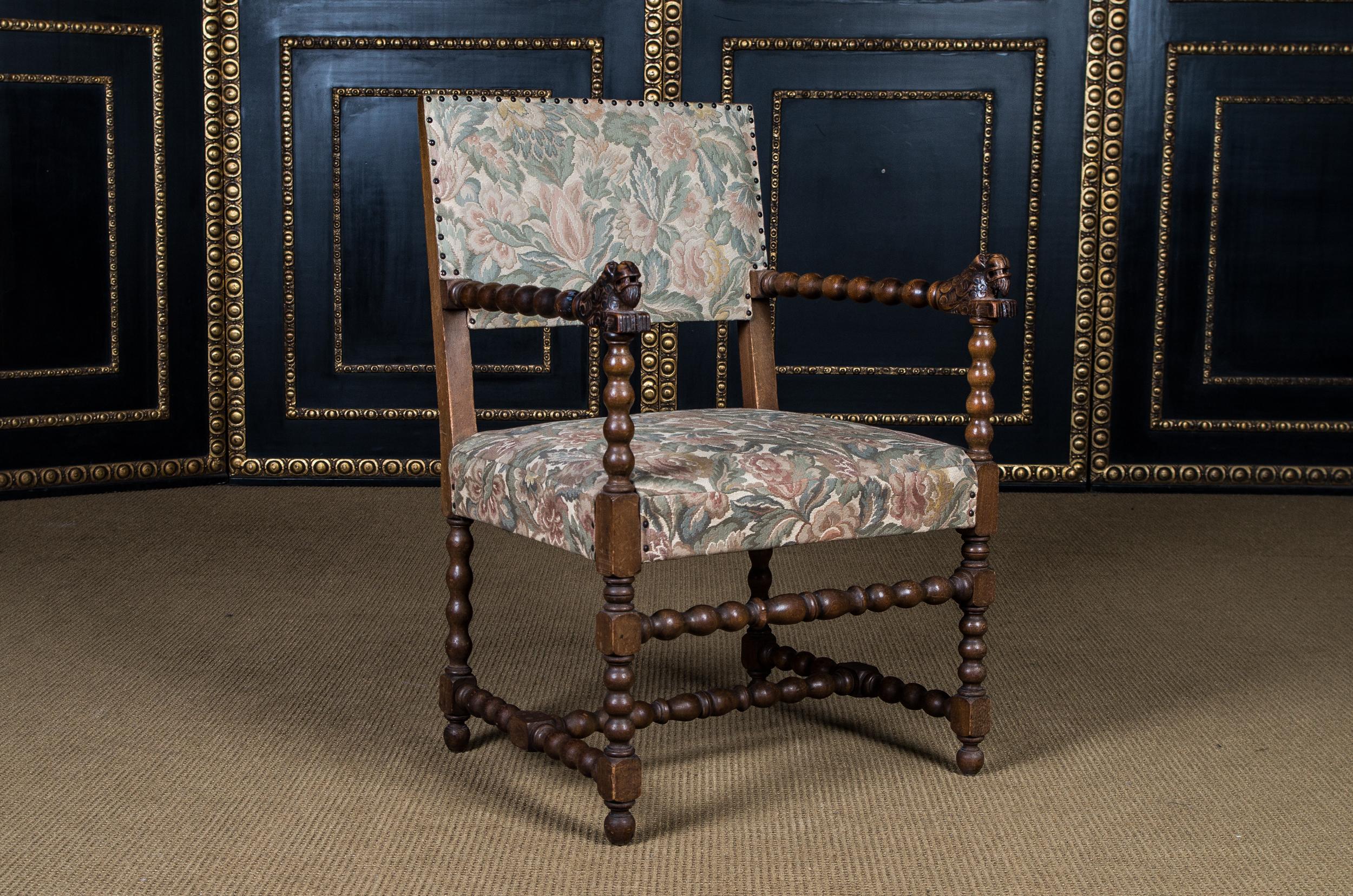 Massive Oak. On four turned legs. Wide seat flanked by two turned armrests. High backrest. Seat and back covered with tapestry in Classic design.