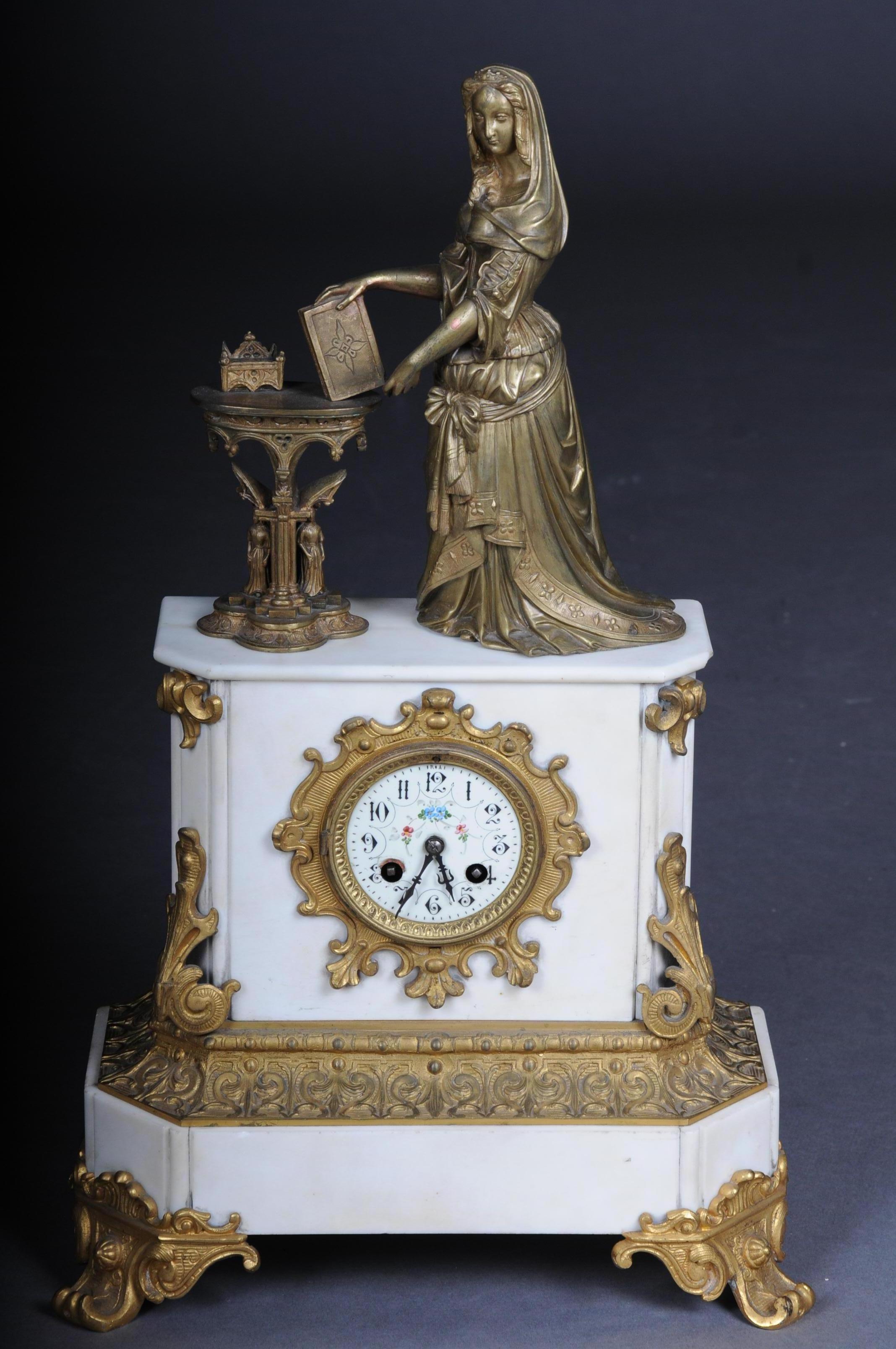 Magnificent historicism clock or mantel clock from circa 1890

On the pedestal there is a figure of a noble lady with a diadem and book at a Gothic table, with writing utensils on it. Enamel dial with arched frieze. Hook walk. Half hour strike on