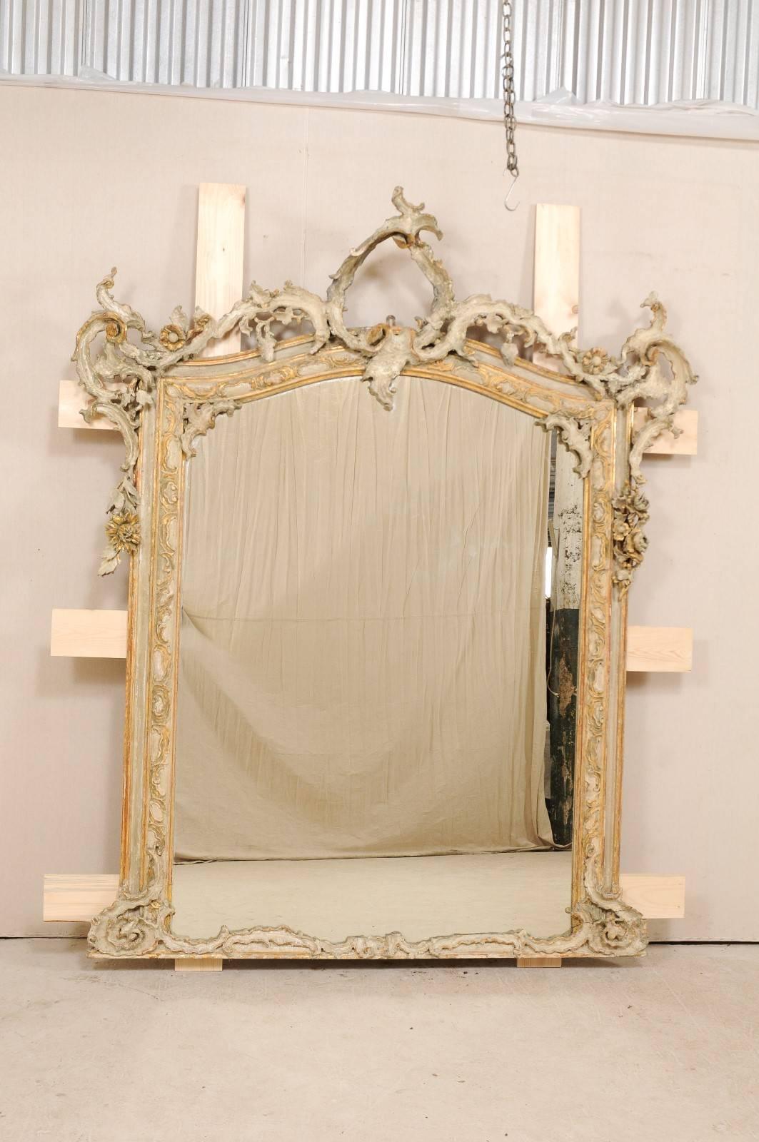 A magnificent Italian Baroque style mirror from the early 19th century. This antique Italian mirror is grand in scale, standing at approximately 7.5 feet tall, and over 6 feet wide. Finely hand-carved Baroque style detailing, in a rich foliage