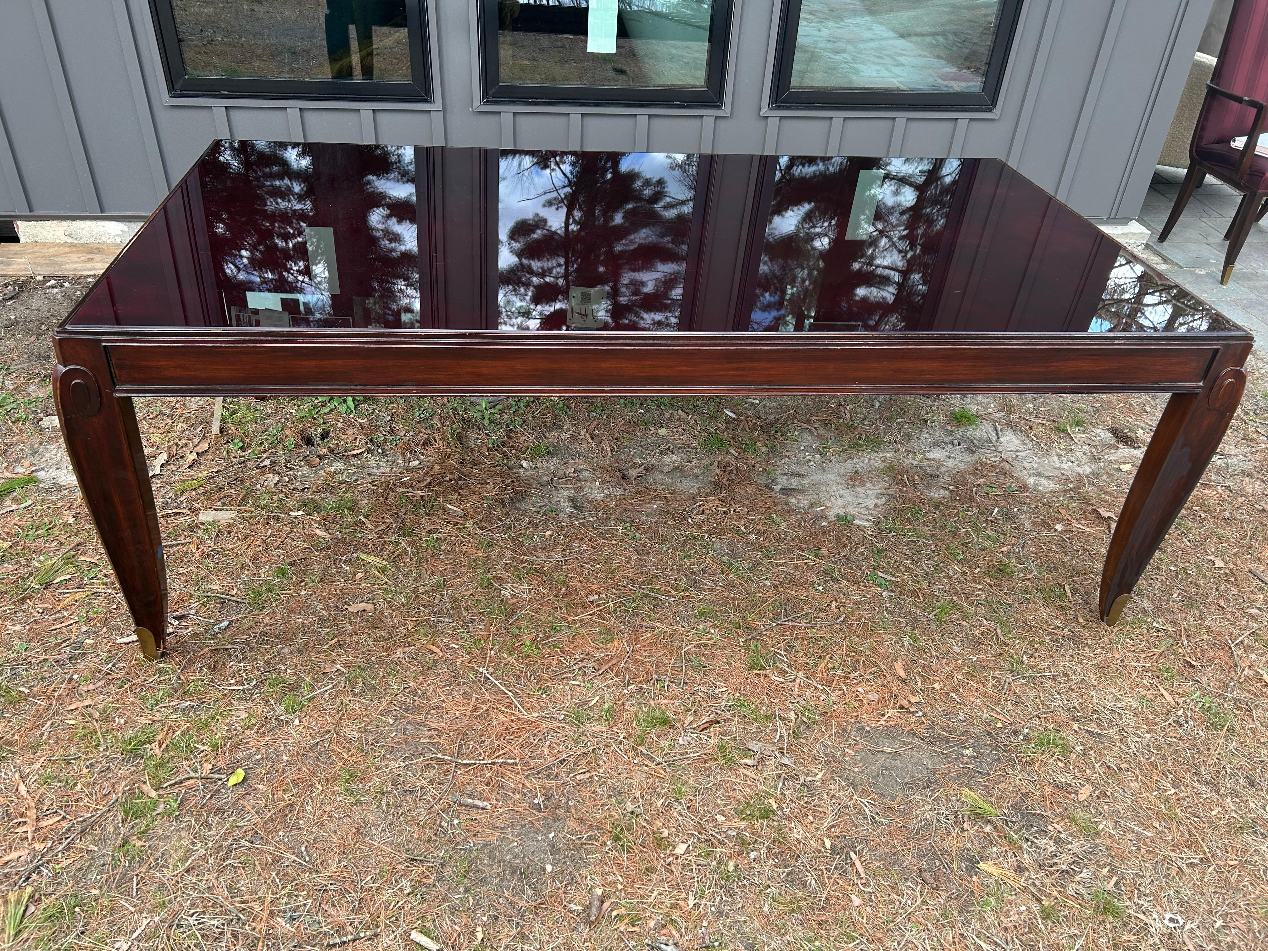 Magnifique table de salle à manger Art Déco Jean Pascaud en acajou et verre.  Le dessus a un insert unique en verre biseauté brun et présente une certaine usure avec quelques égratignures - voir les photos.  Les pieds de la table sont très