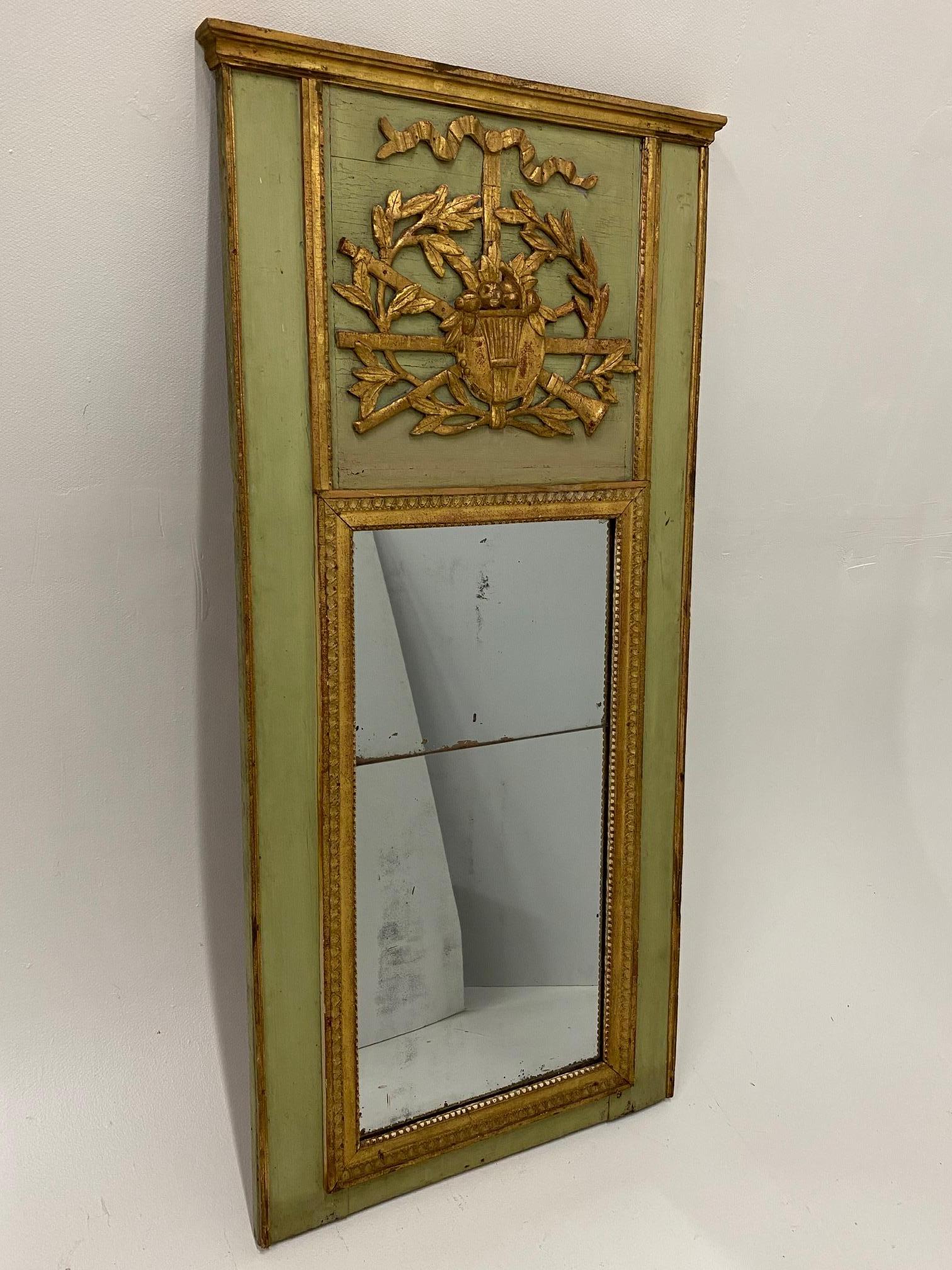 A beautiful 18th century painted vertical giltwood trumeau mirror having a gorgeous soft green painted frame with gilt musical themed embellishments. Original mirror in very good condition, has the Classic two pieces with horizontal seam.