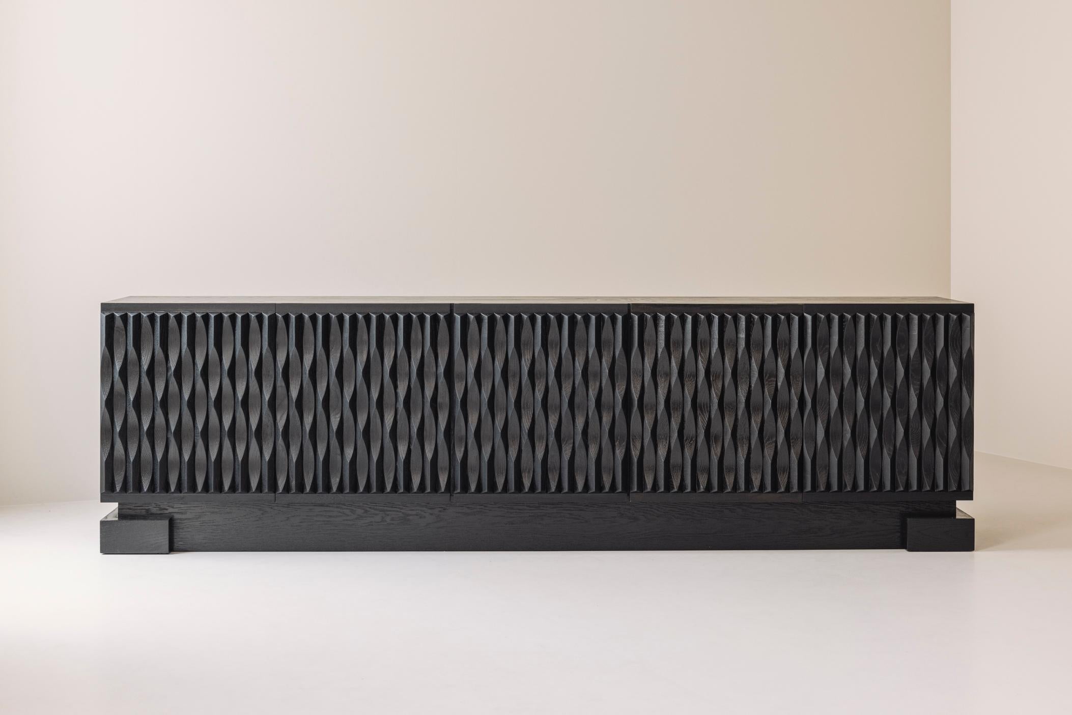 Magnificent large brutalist sideboard from Belgium, designed and manufactured during the 1970s. This credenza is fully made out of dark stained oak and features beautiful sculpted doors. On the left a series of five drawers, the other doors covering