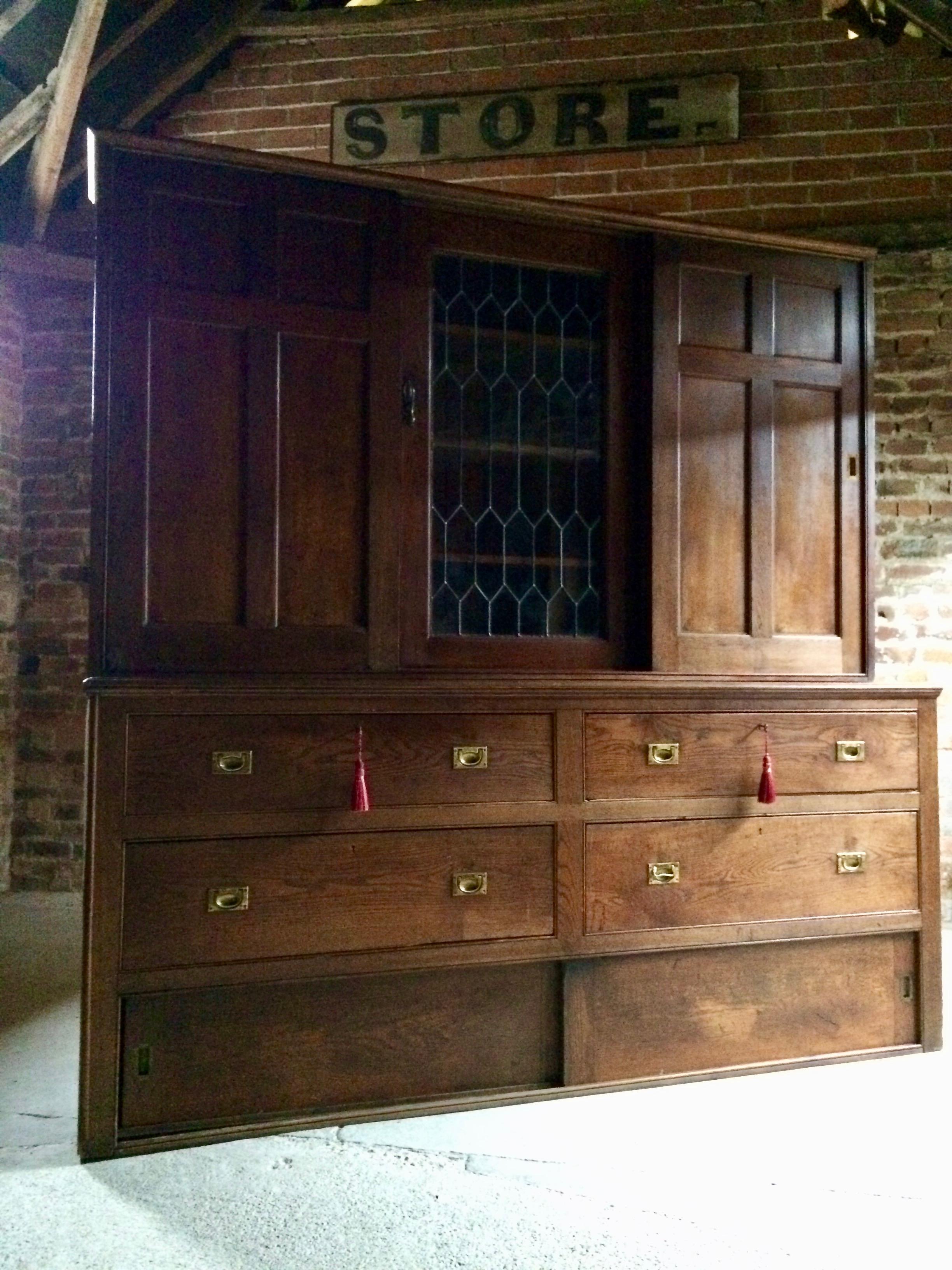 A magnificent early 20th century Edwardian Haberdashery oak shop fitting cabinet of extremely large proportions circa 1905, having a moulded frieze above two sliding doors and a central astragal glazed door containing shelves within, the top resting