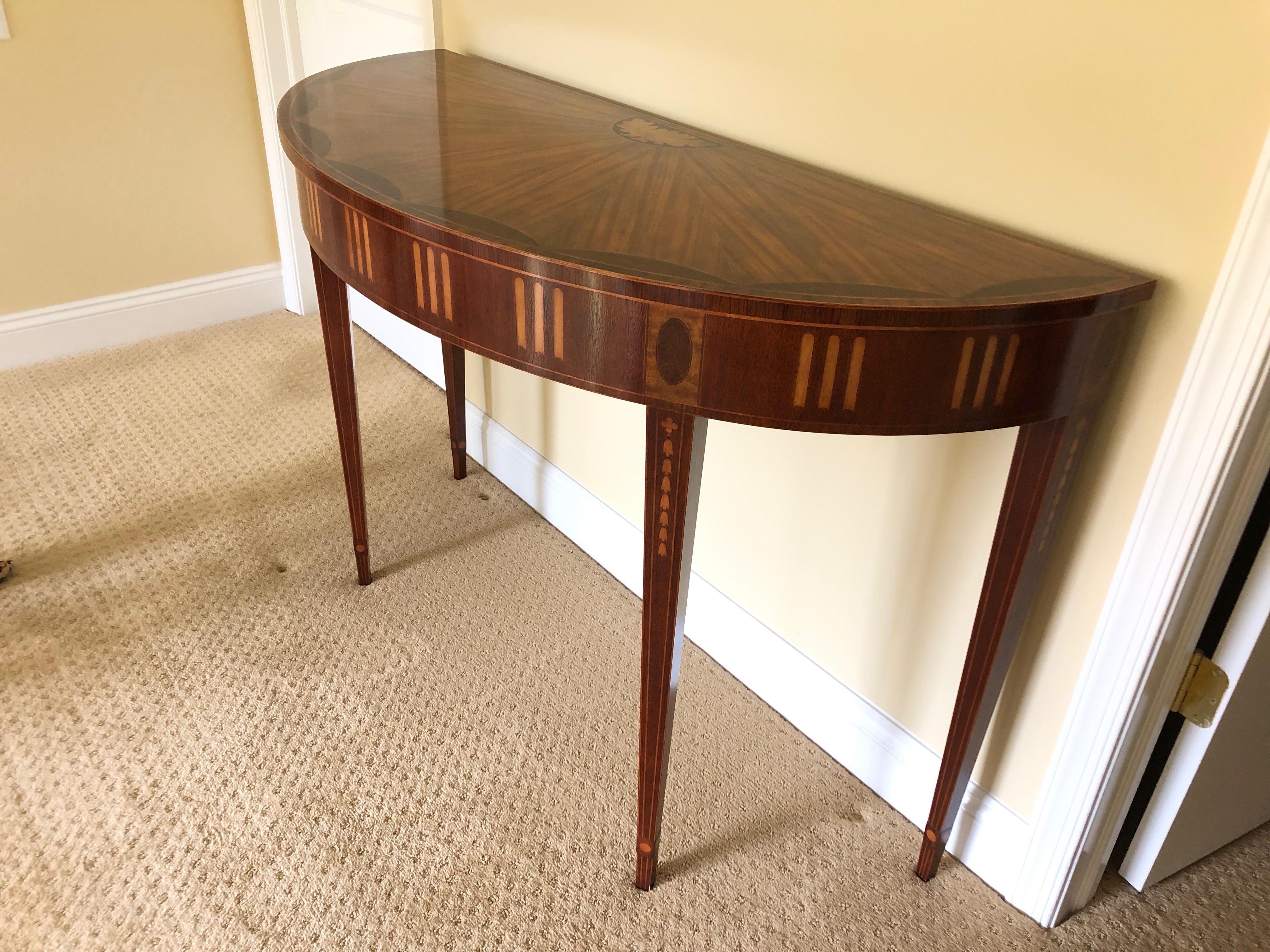 Gorgeous demilune having incredible inlaid details with a mix of woods including mahogany, satinwood and ebony, having lovely acorn decoration at the top back with amazing grain on top that fans outward. The legs are elegantly tapered and also