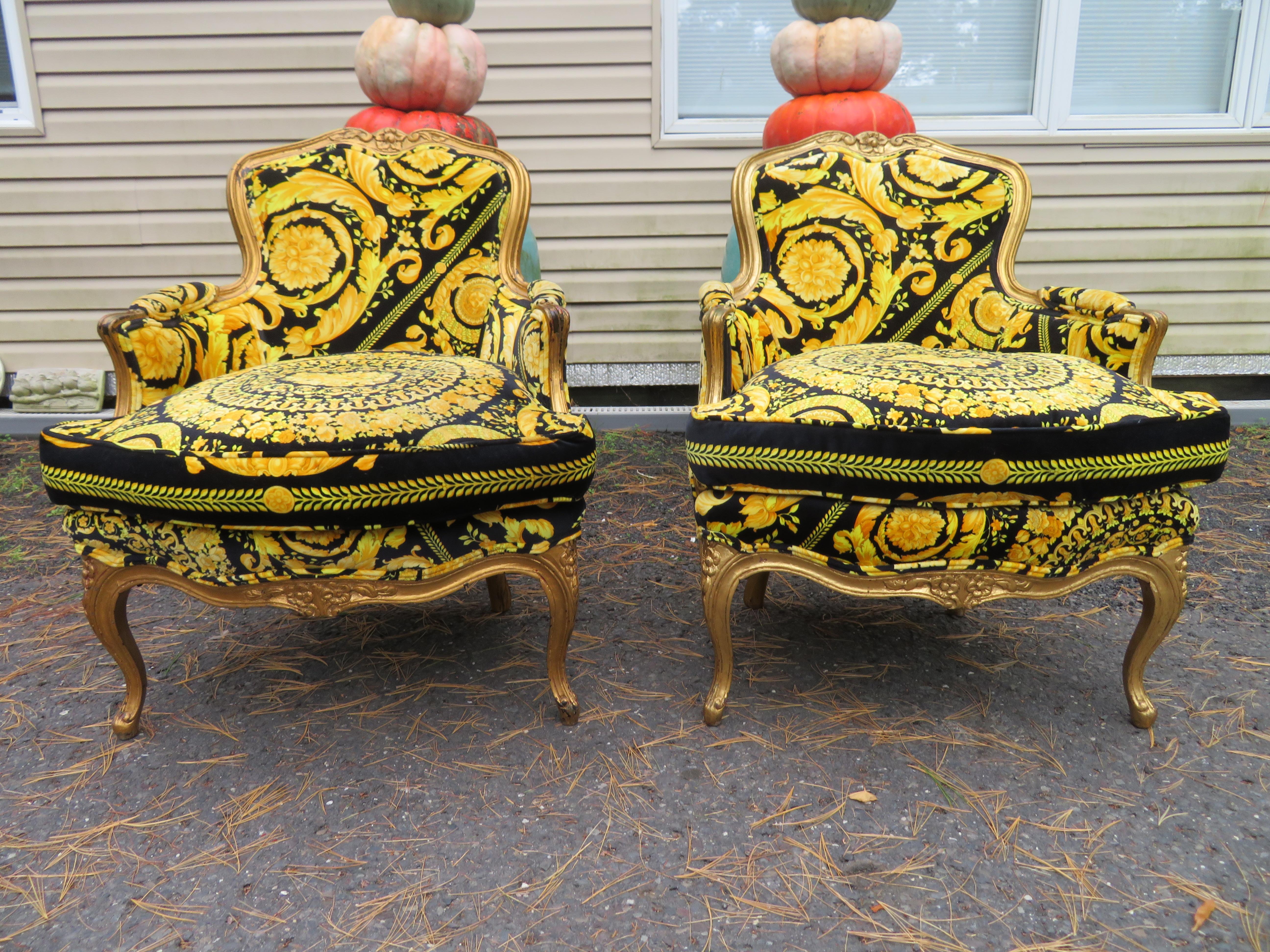 Magnificent pair of gilded French Louis 15th style carved chairs with custom Versace fabric. We absolutely love the gilded gold intentionally distressed finish along with the amazing Versace velvet fabric. These chairs measure 32