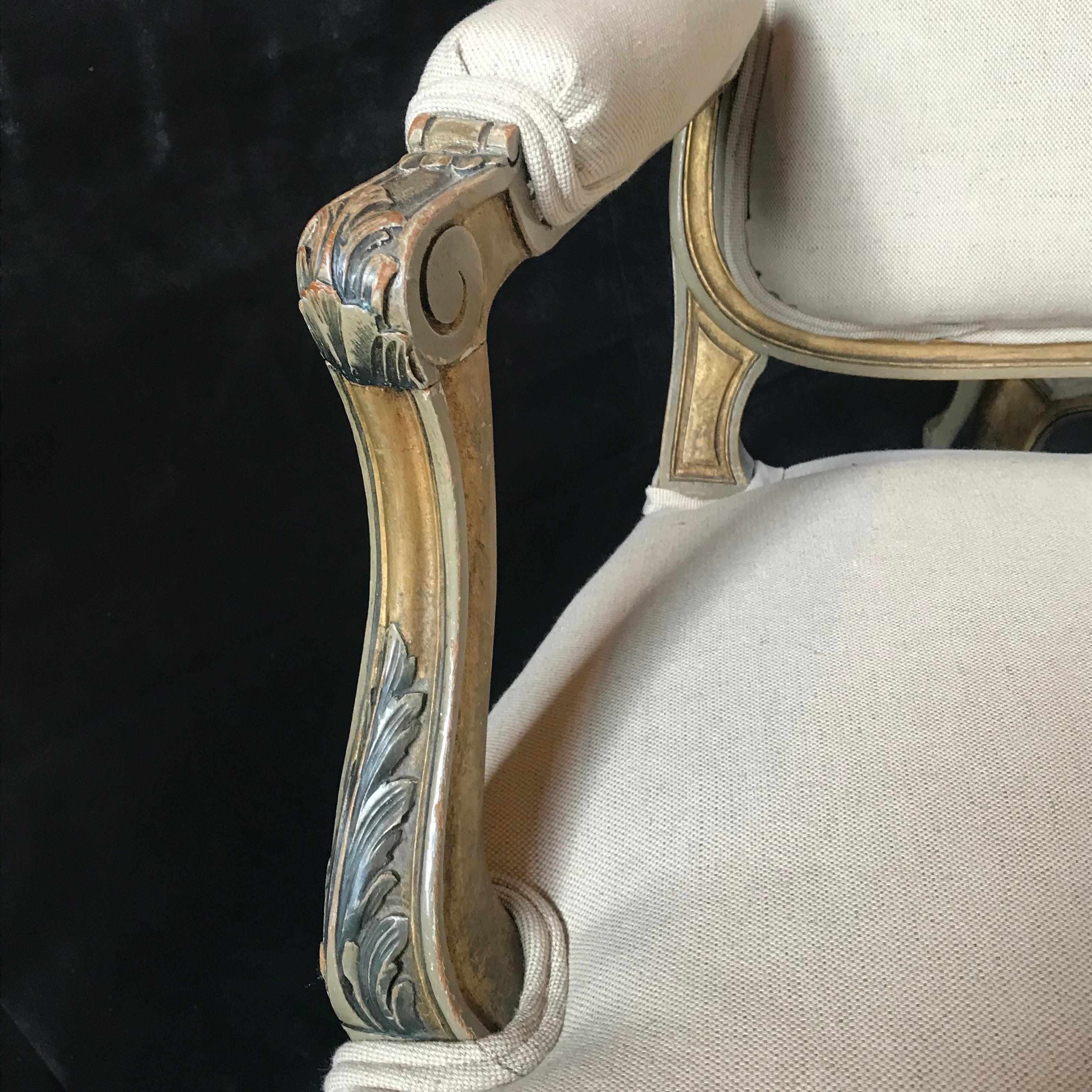 A stately Classic pair of carved wood French armchairs with original paint, gold with a little gray, as well as fresh new neutral cotton linen upholstery.
Measures: Chairs back height 38”, width 27”, seat height 18”, arm height 25 1/2”.