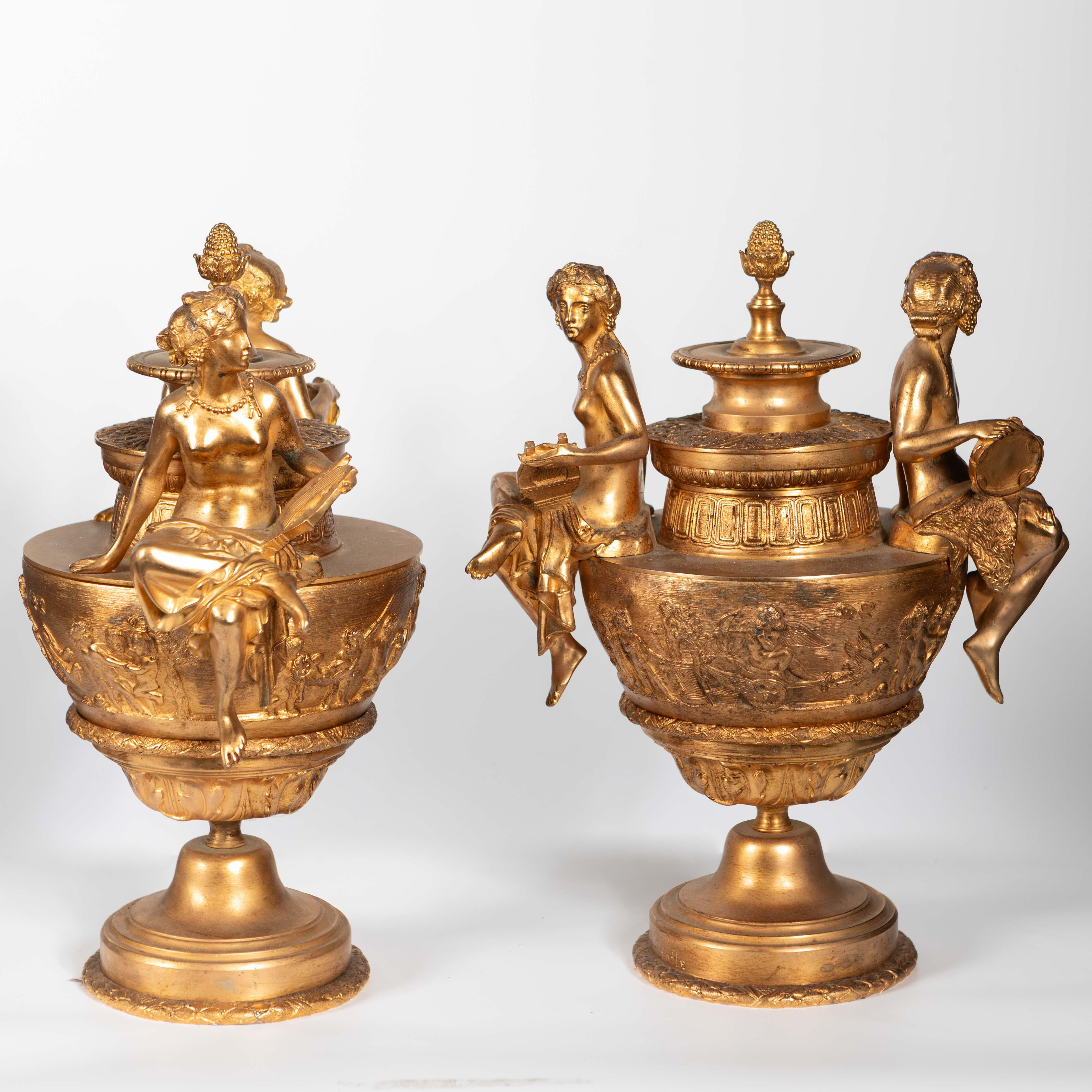 Bedeutendes Paar neoklassizistischer Urnenvasen aus vergoldeter Bronze, signiert Christofle auf rundem Sockel, im neoklassizistischen Stil des späten 19. Aufwendig dekoriert mit sitzenden Figuren, die Musikinstrumente halten, Allegorie auf die