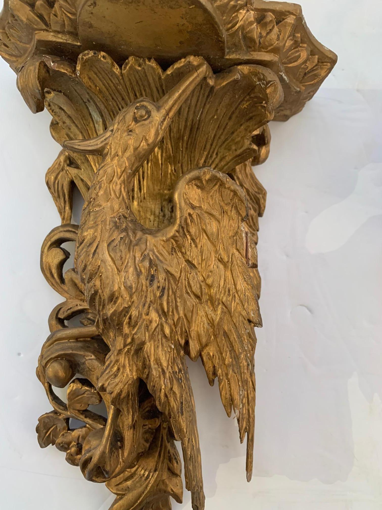 A pair of beautifully carved giltwood wall brackets having striking beaked birds that support platforms for displaying objet d'arte.