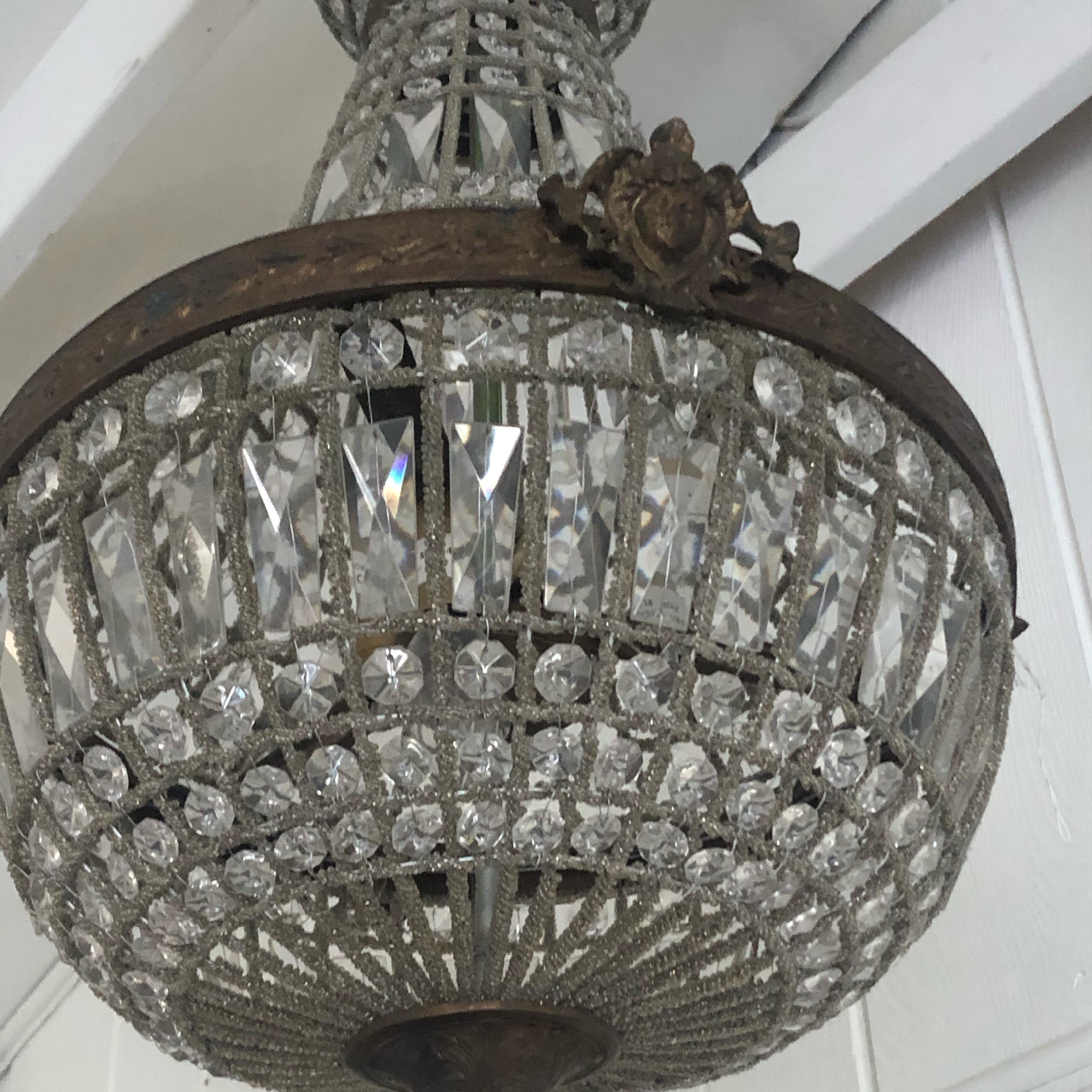 A romantic pair of Empire style French antique pendant chandeliers having elaborate bronze leaf motife top and putti decorated surround. The meticulous crystal necklaces have two shapes with balloon top and bottom. 
3 lights inside each. Ceiling cap