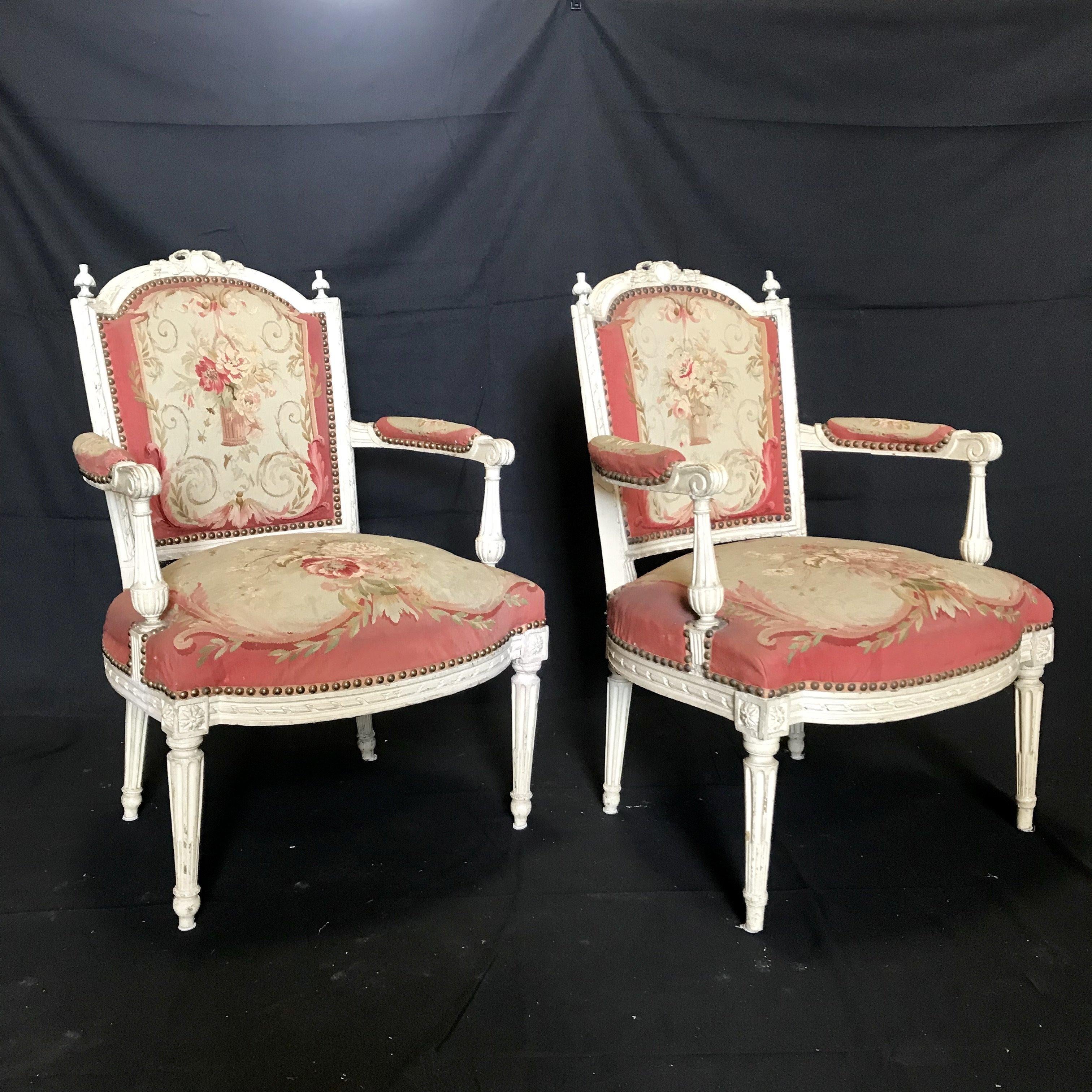 Due delle più belle sedie fauteuil francesi che abbiamo mai visto, con telai in legno ornatamente intagliati e dipinti e tappezzeria originale in arazzo Aubusson con imbottitura e molle in crine di cavallo. Il motivo floreale color lampone, crema e