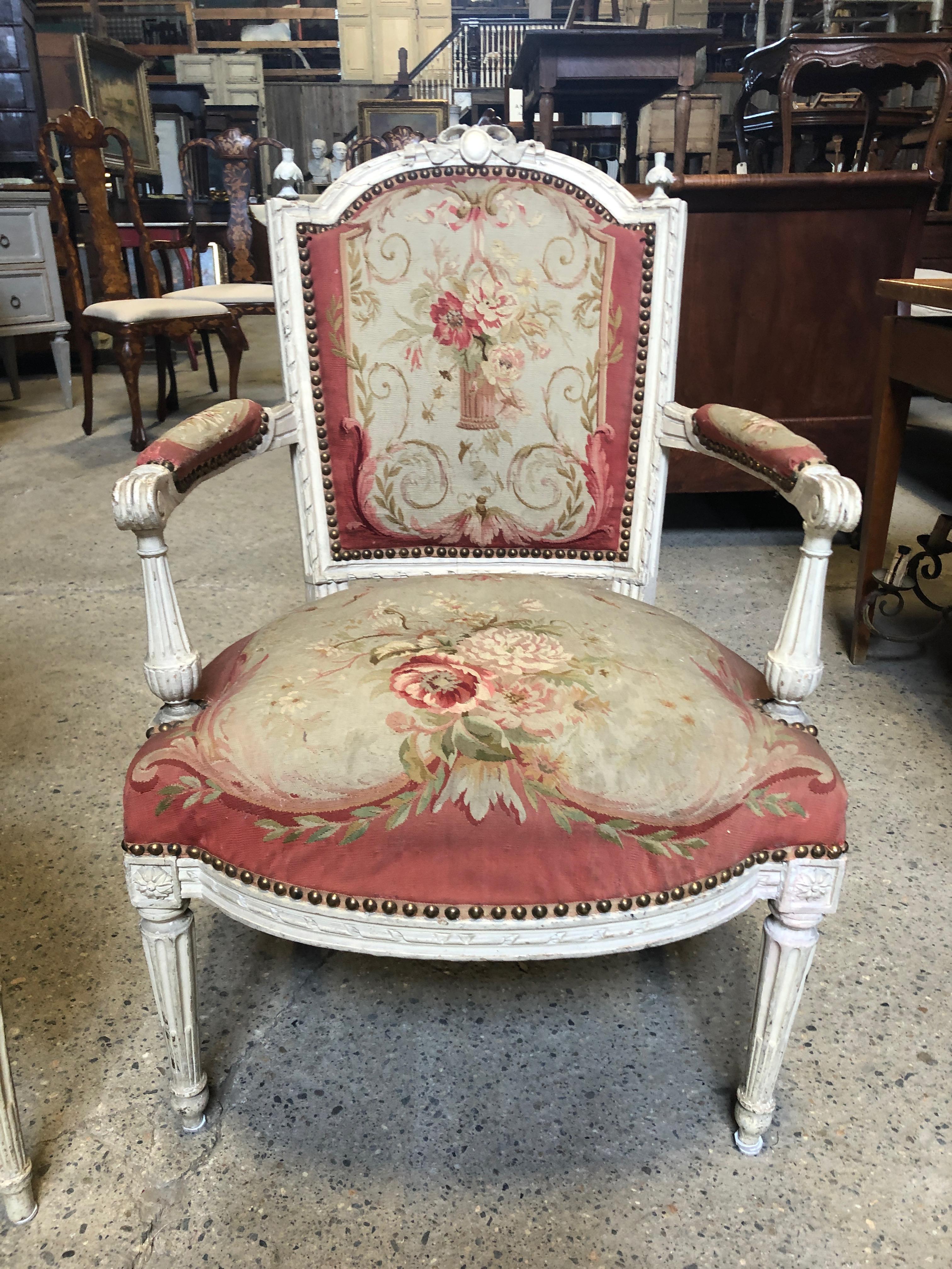 Two of the prettiest French fauteuil chairs we've ever seen having ornately carved wood painted frames and original tapestry Aubusson upholstery with horsehair stuffing and springs. The rasberry, cream and soft green floral pattern is finished with