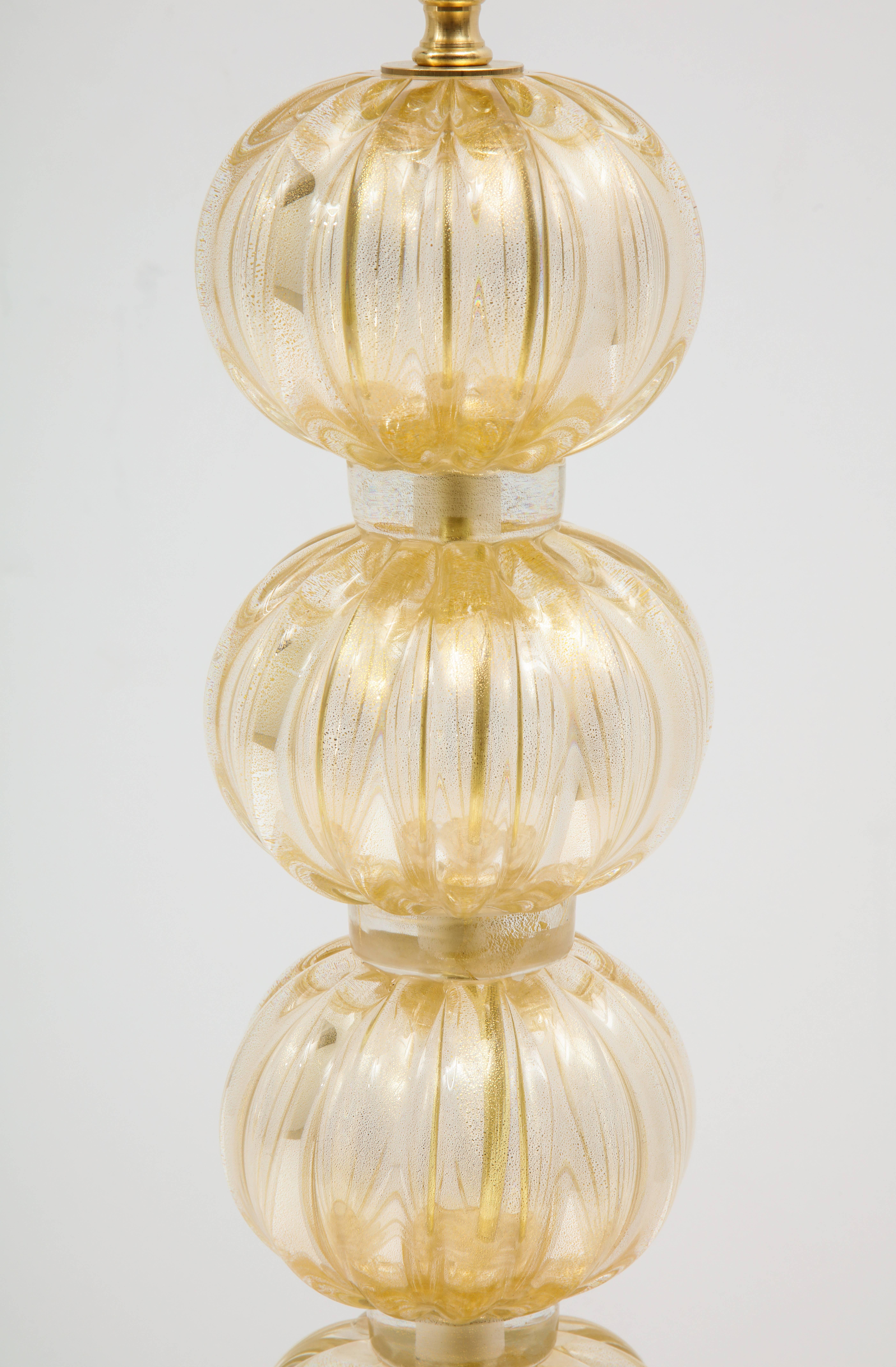 Pair of Italian Murano Gold lamps consisting of clear glass infused with 23-karat gold, creating a rich and luminous effect. Each of the four ridged spheres are separated by glass rings with gold flecks and all sit atop a ridged glass oval cup,