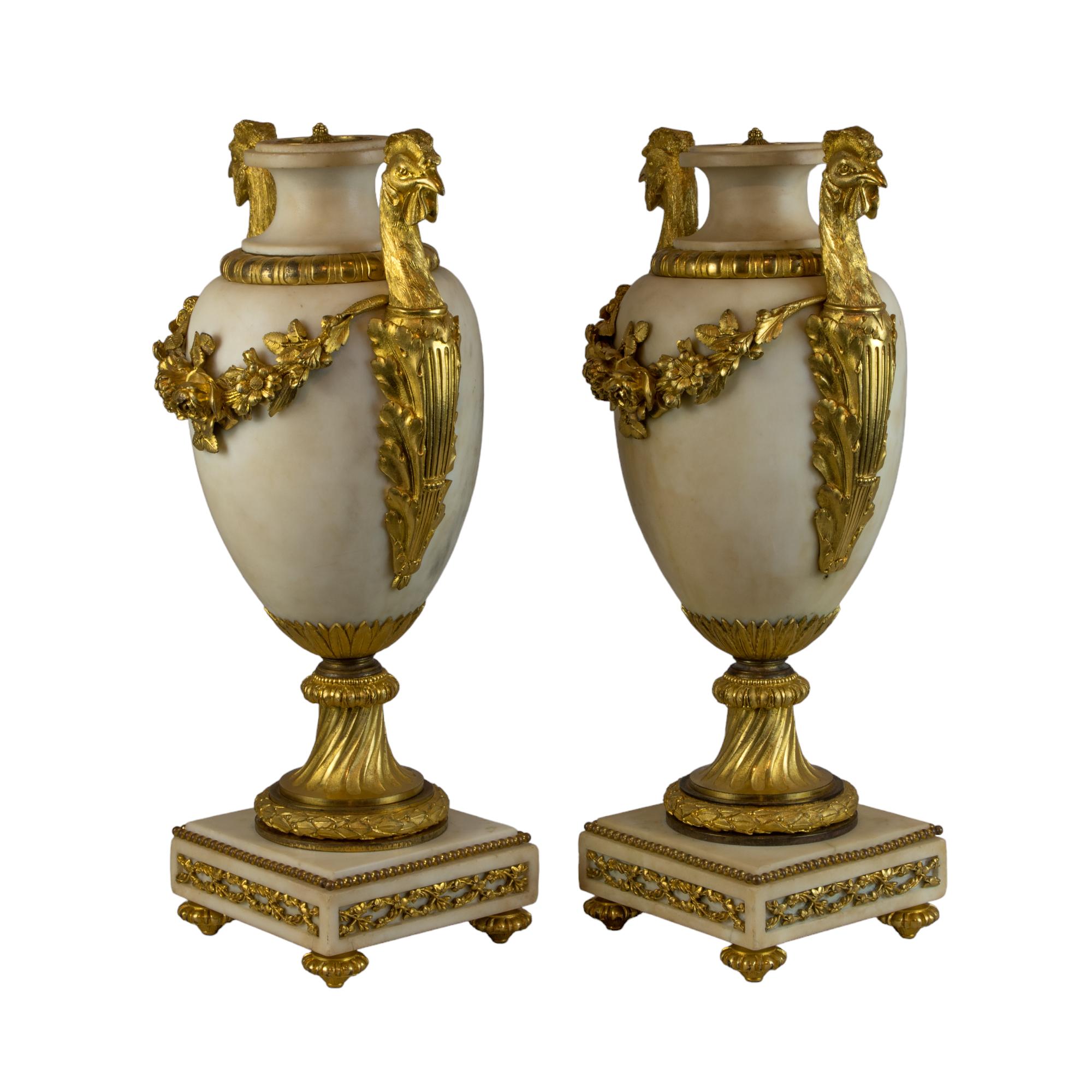 A distinguished pair of Louis XVI style gilt-bronze-mounted white marble urns, epitomizing the neoclassical taste of the 19th century with a harmonious blend of utility and grandeur. Each urn stands as a testament to exquisite craftsmanship,