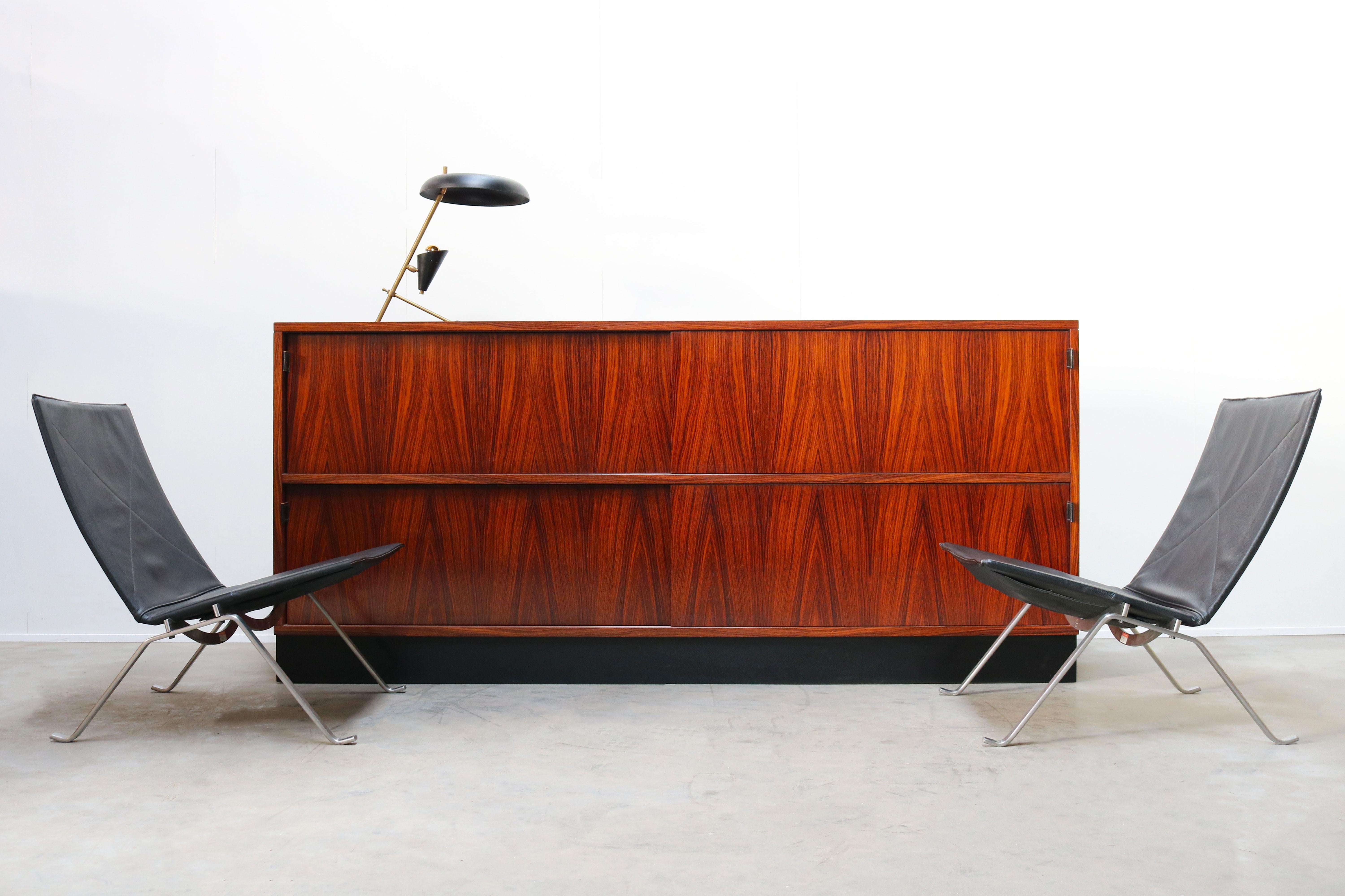 Magnificent large rosewood sideboard by Florence Knoll for Knoll International in the 1950s. The sideboard has 4 sliding doors with black leather grips. Wonderful rosewood grain that looks Royal and warm. The rosewood combines perfectly with the