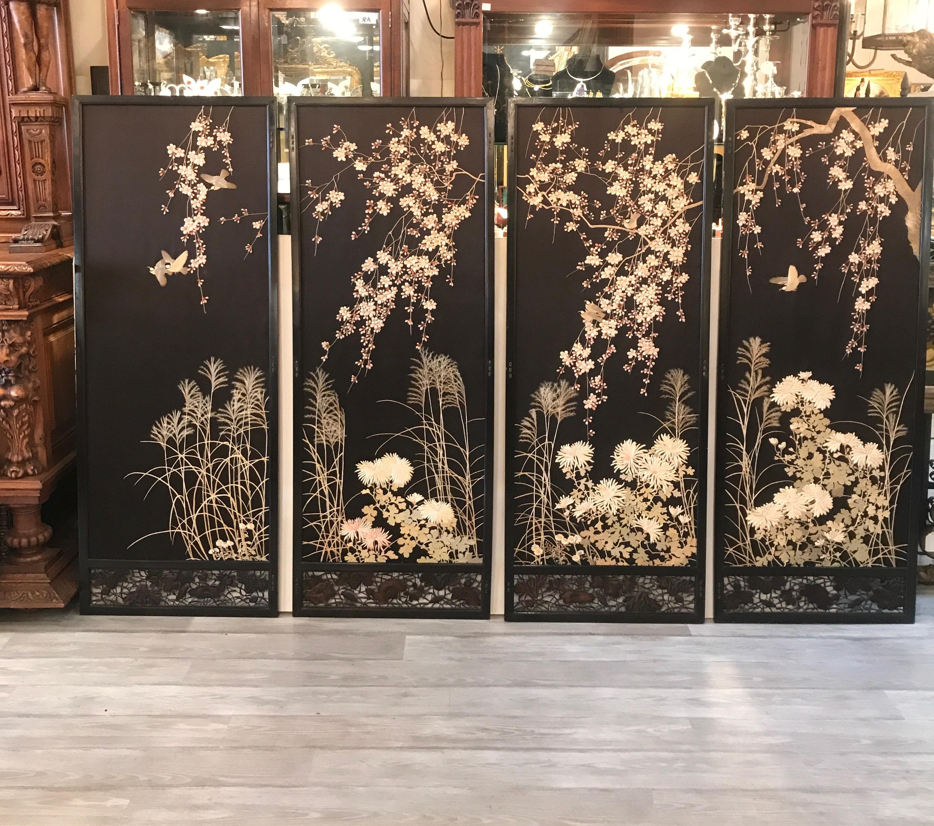 A set of four hand needlework silk panels in black lacquered frames. The panels with a black silk background with embroidered cherry blossoms, birds and spider mum florals. The high quality and expert talent of the needlework done by a Japanese