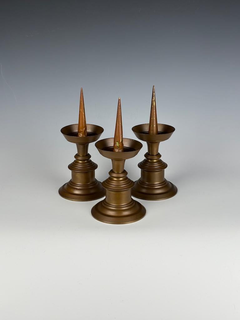 Gli squisiti candelabri in bronzo, risalenti alla fine del XVII o all'inizio del XVIII secolo, sono una magnifica testimonianza della durevole maestria dell'epoca. Questo raro e completo set di tre esemplari, un vero e proprio reperto per ogni